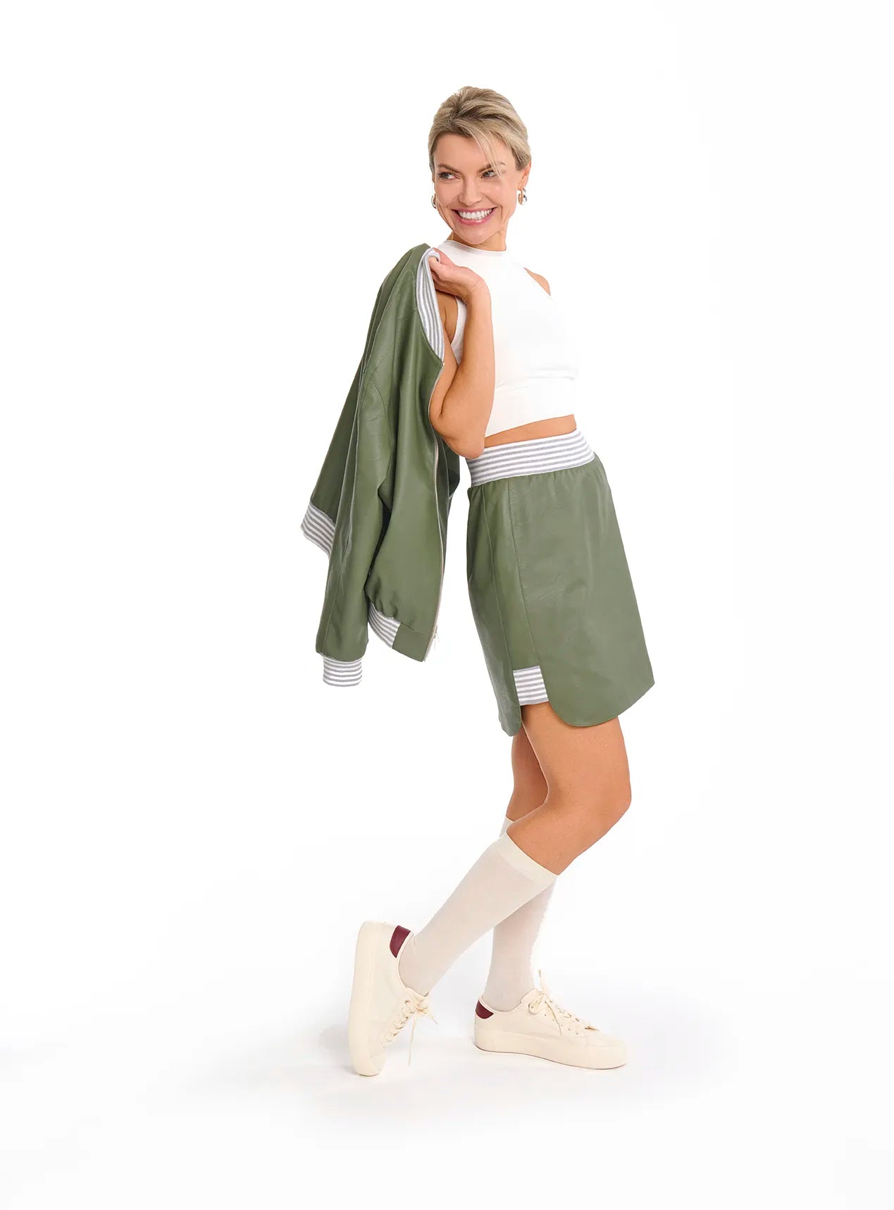 A woman in a green Mimaussy Paris 90s style skirt paired with a white top, showcasing a vintage fashion look.