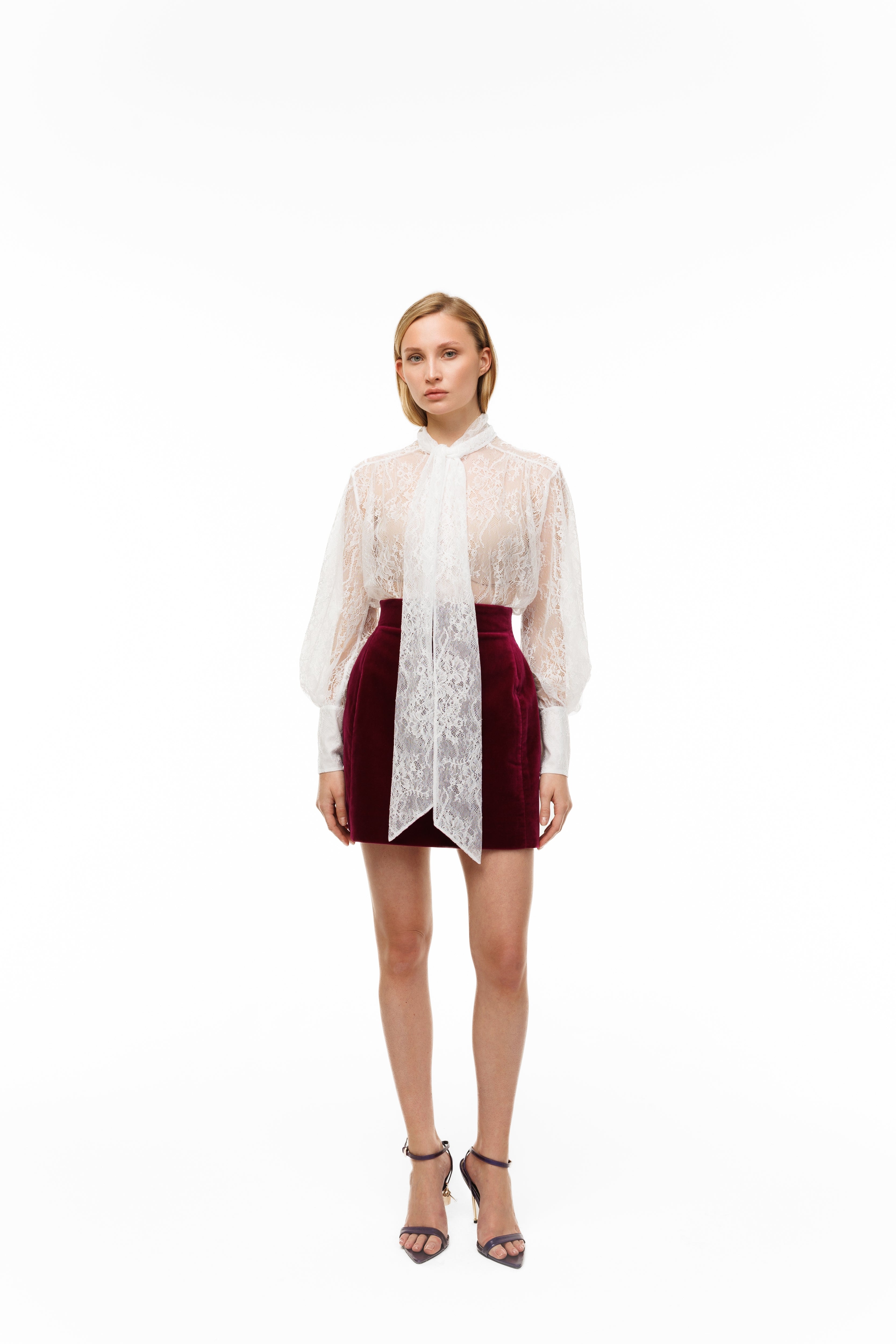 Woman wearing a sheer white blouse with a red skirt on a white background