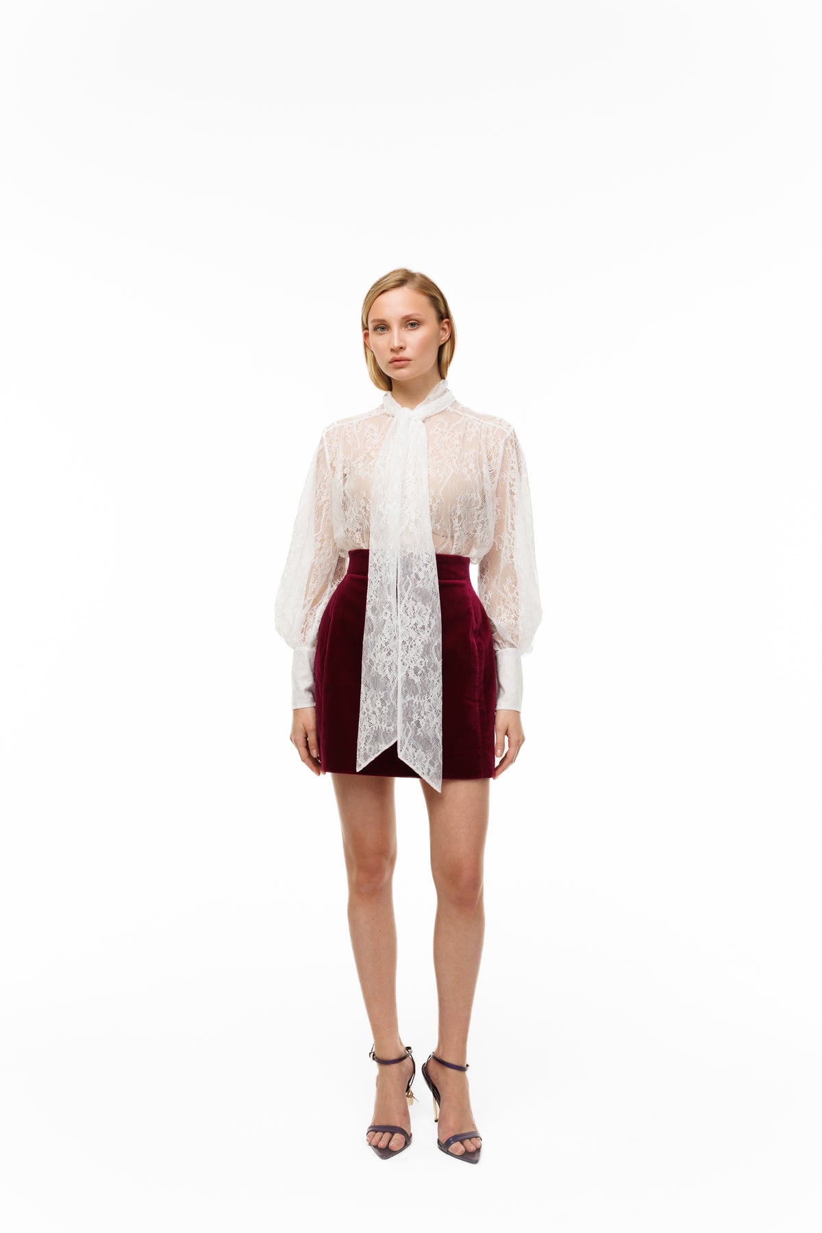 Woman wearing a sheer white blouse with a red skirt on a white background