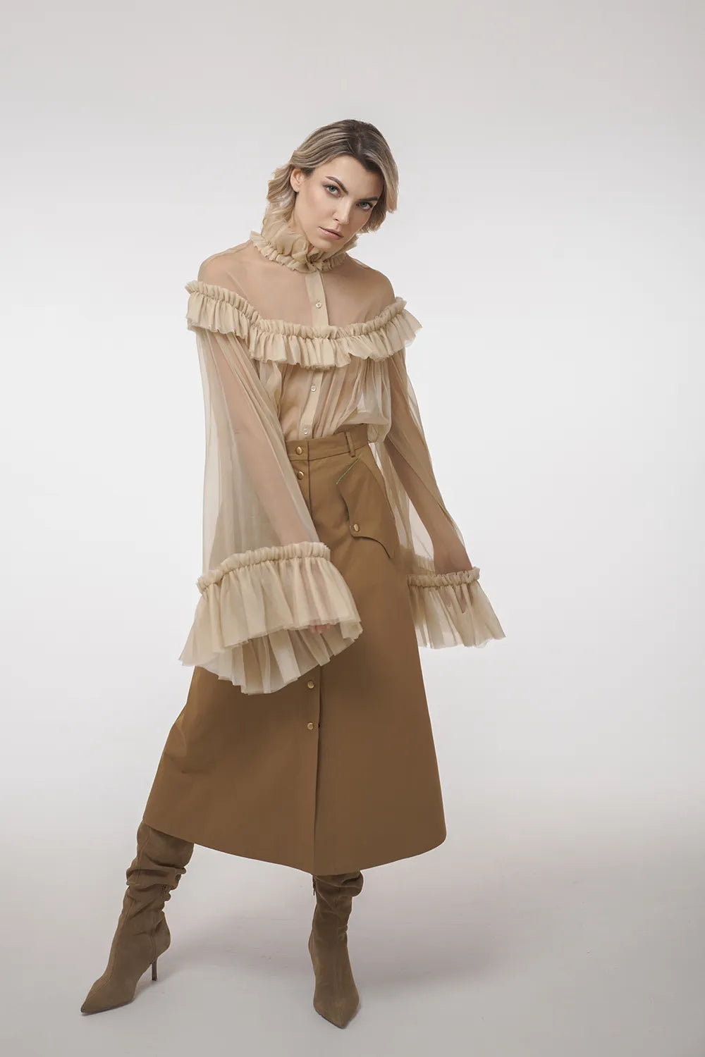 A woman models a beige A-line skirt with vintage fabric inserts and a sheer top, representing Mimaussy Paris's fashion line.