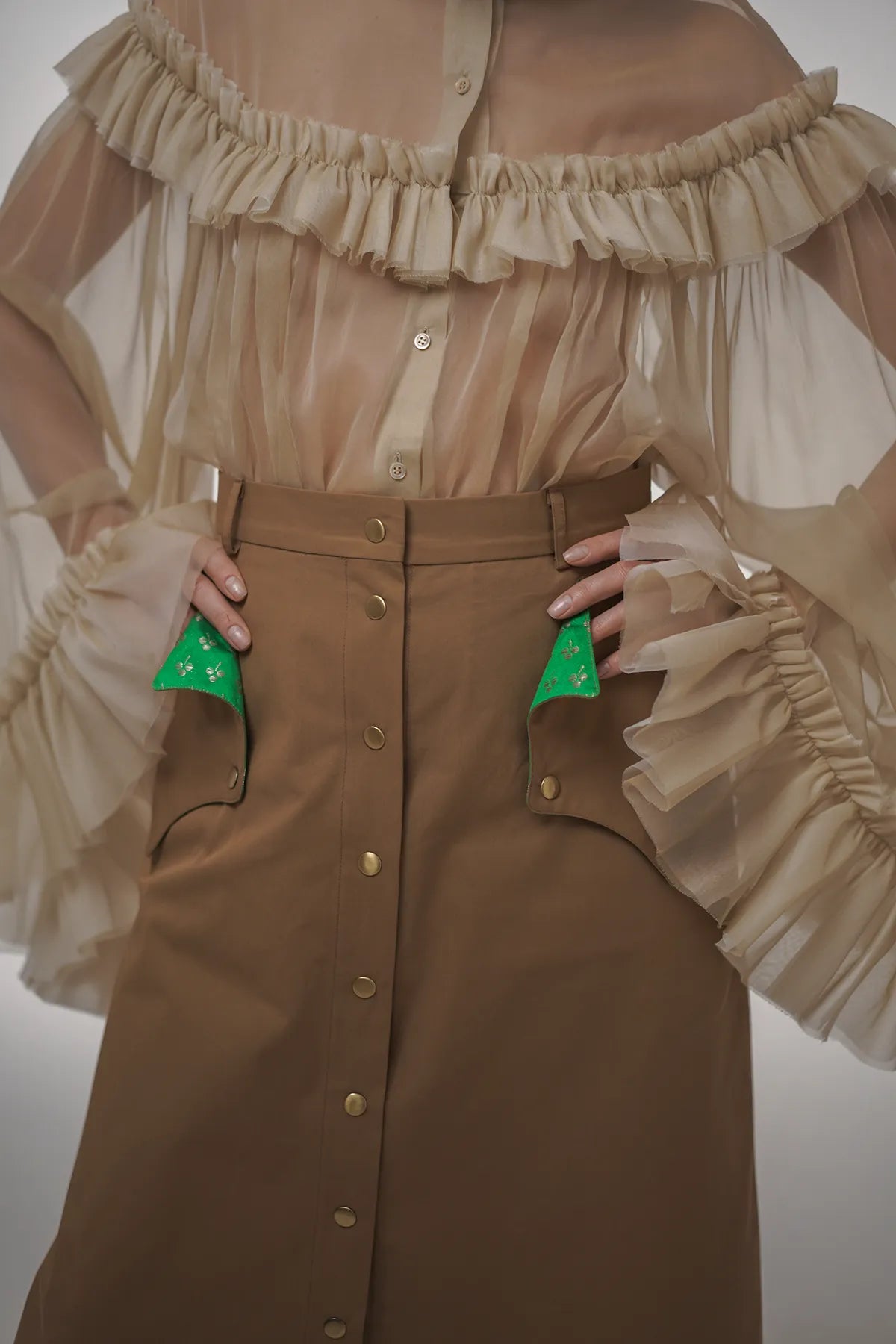 A woman wearing a toffee glaze A-line skirt with green buttons and vintage fabric inserts by Mimaussy Paris.