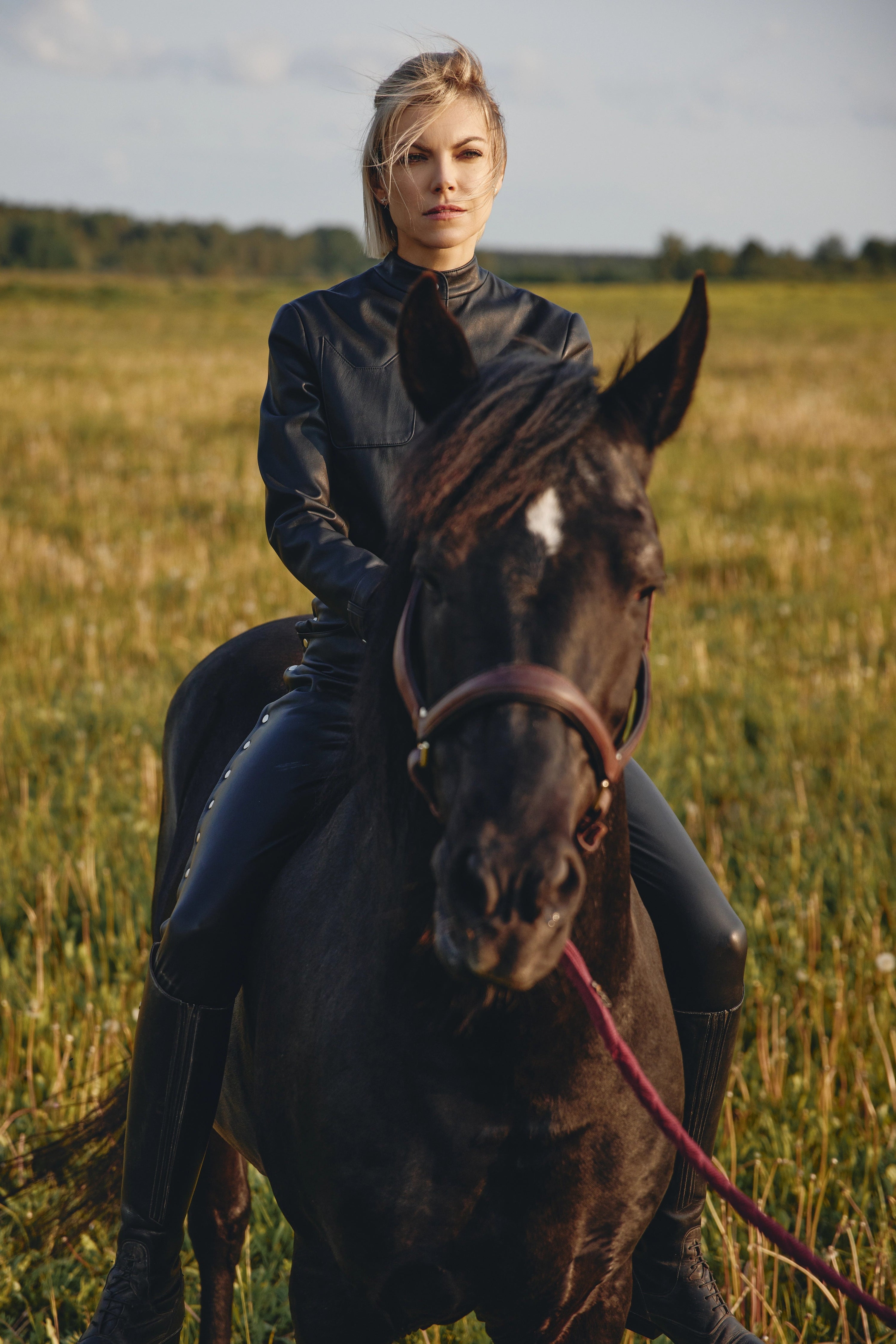 Woman wearing Amazone Pants from Mimaussy Paris, riding a horse in an open field under a clear sky