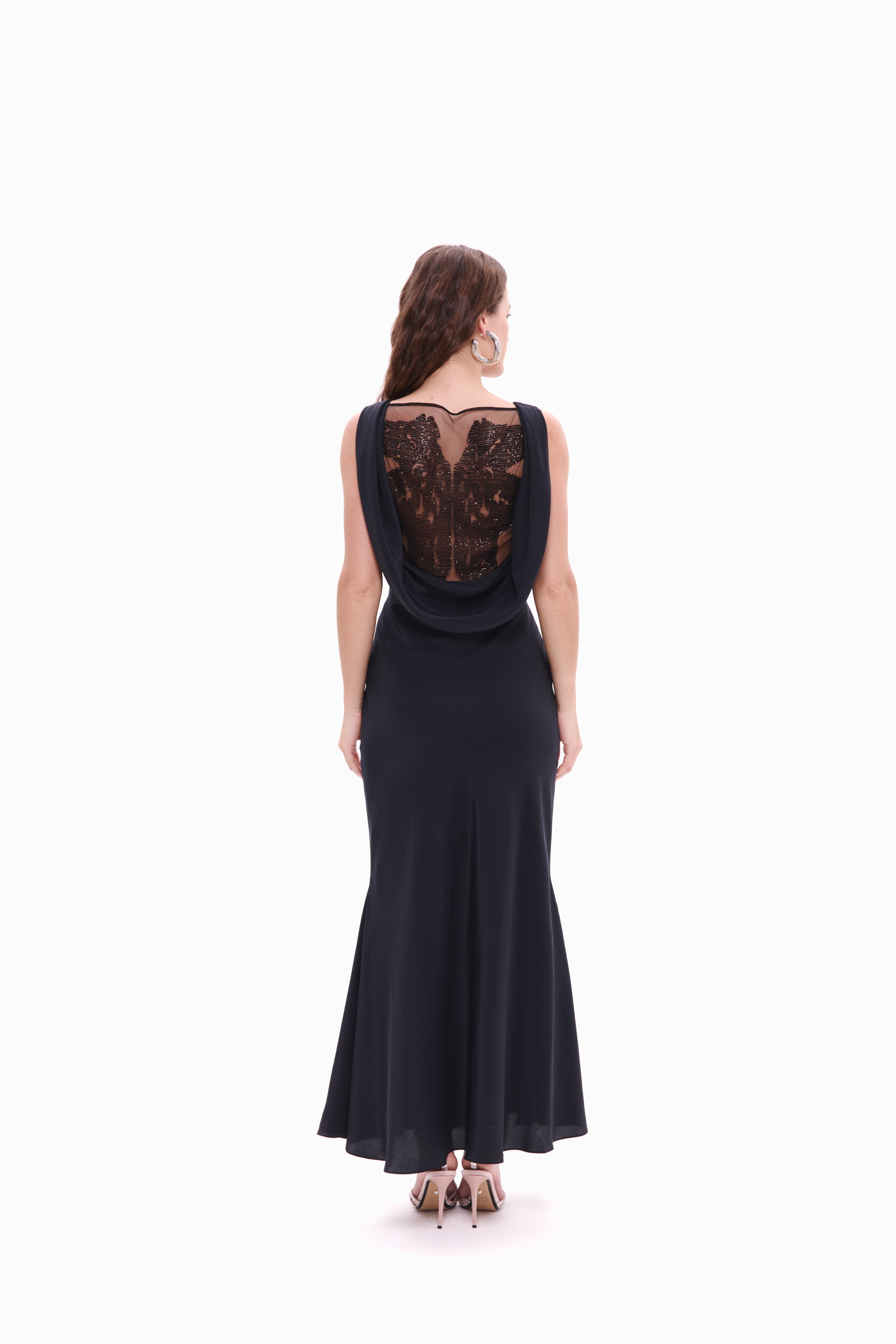 Woman wearing a black evening gown with lace detailing on a white background