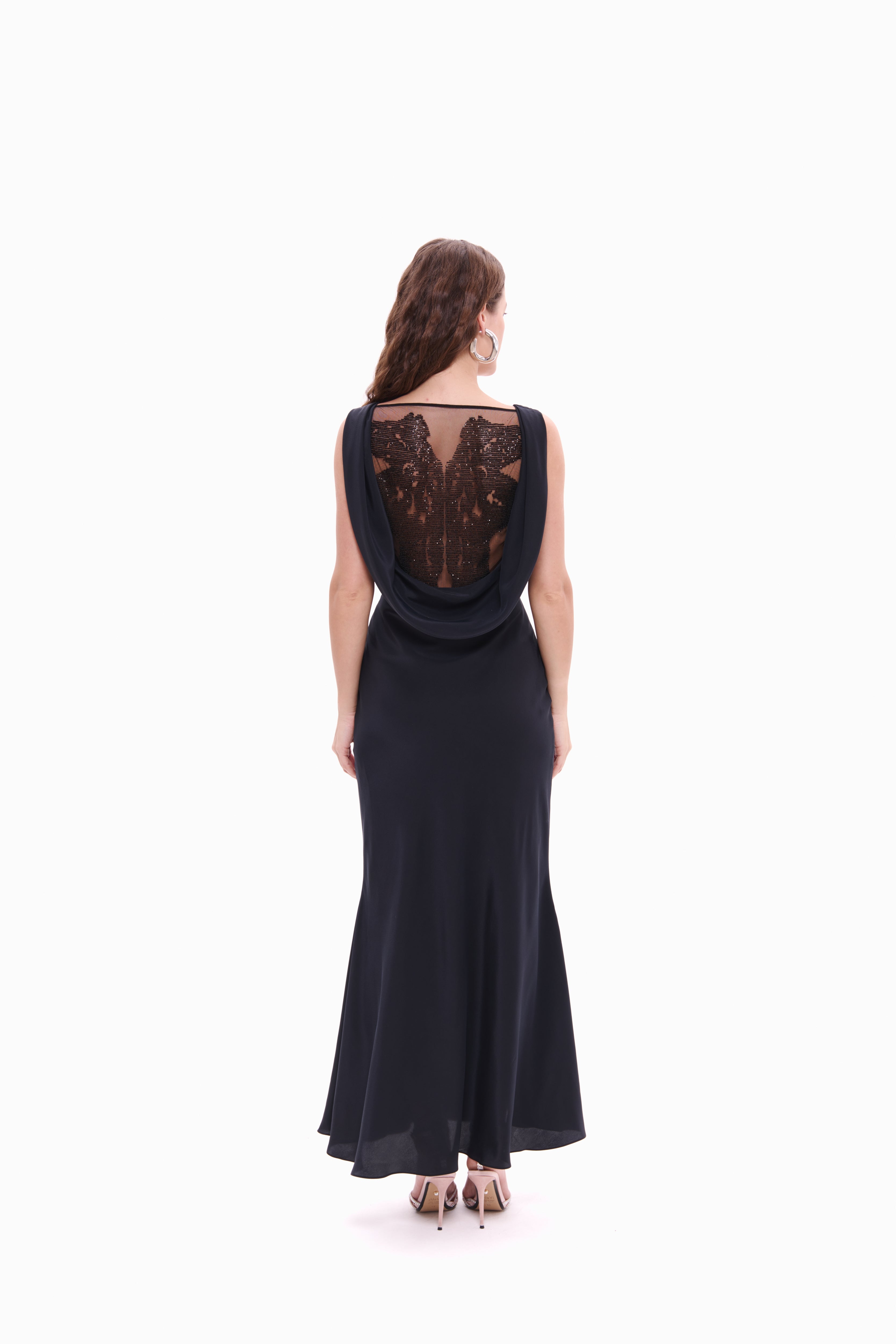 Woman wearing a black evening gown with lace detailing on a white background