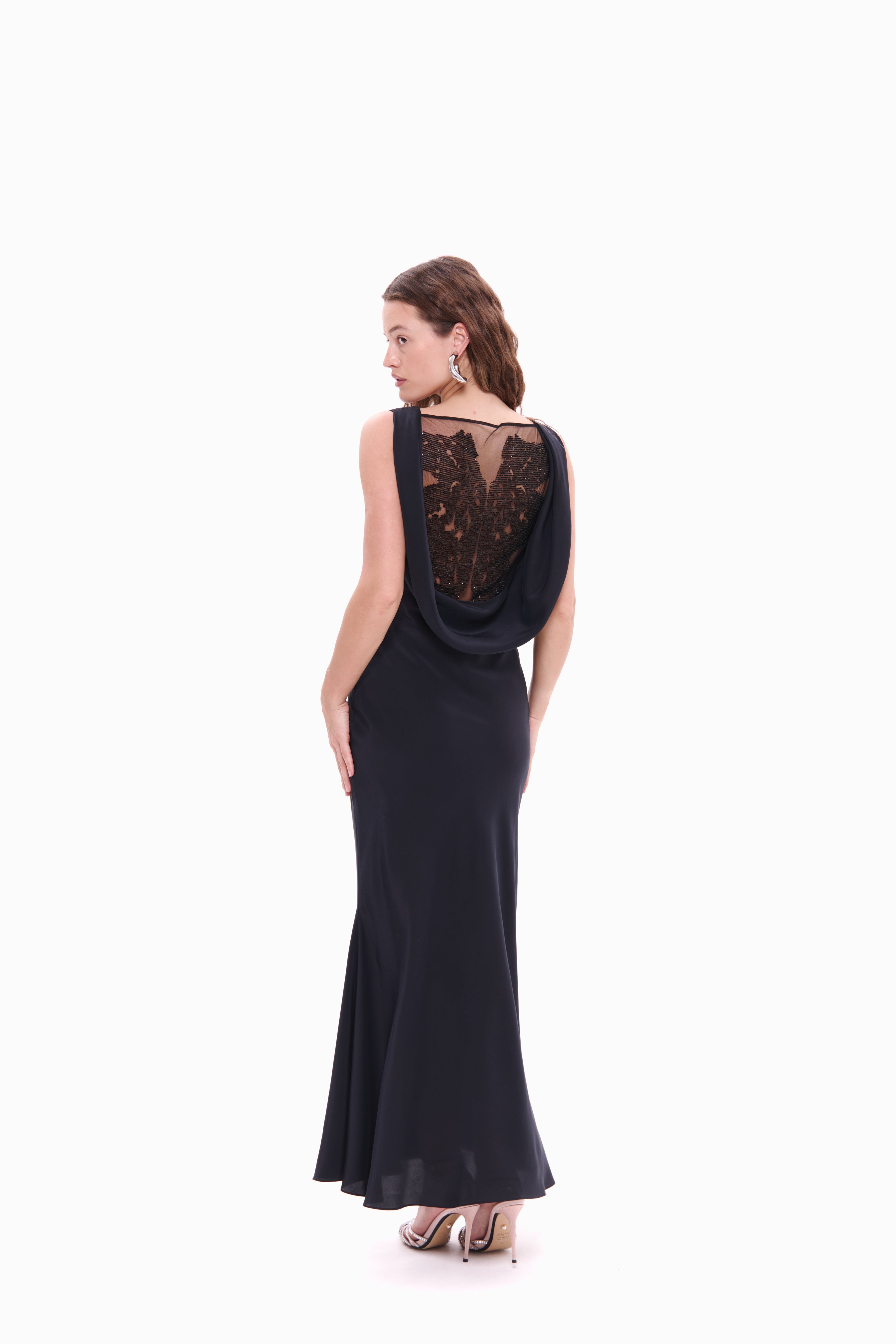 Woman wearing a black evening gown with lace detailing on a white background