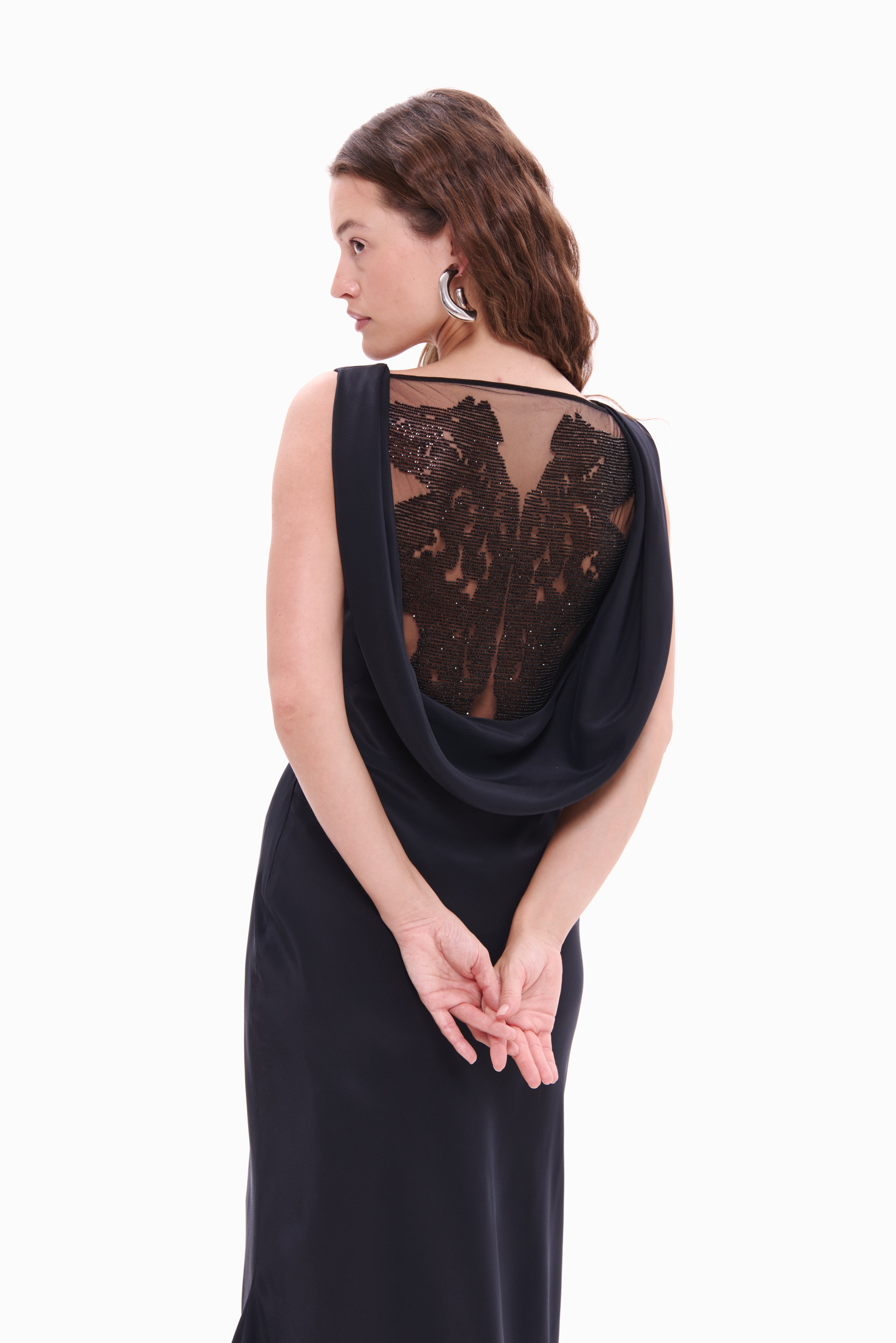 Woman wearing a black evening gown with a lace back on a white background