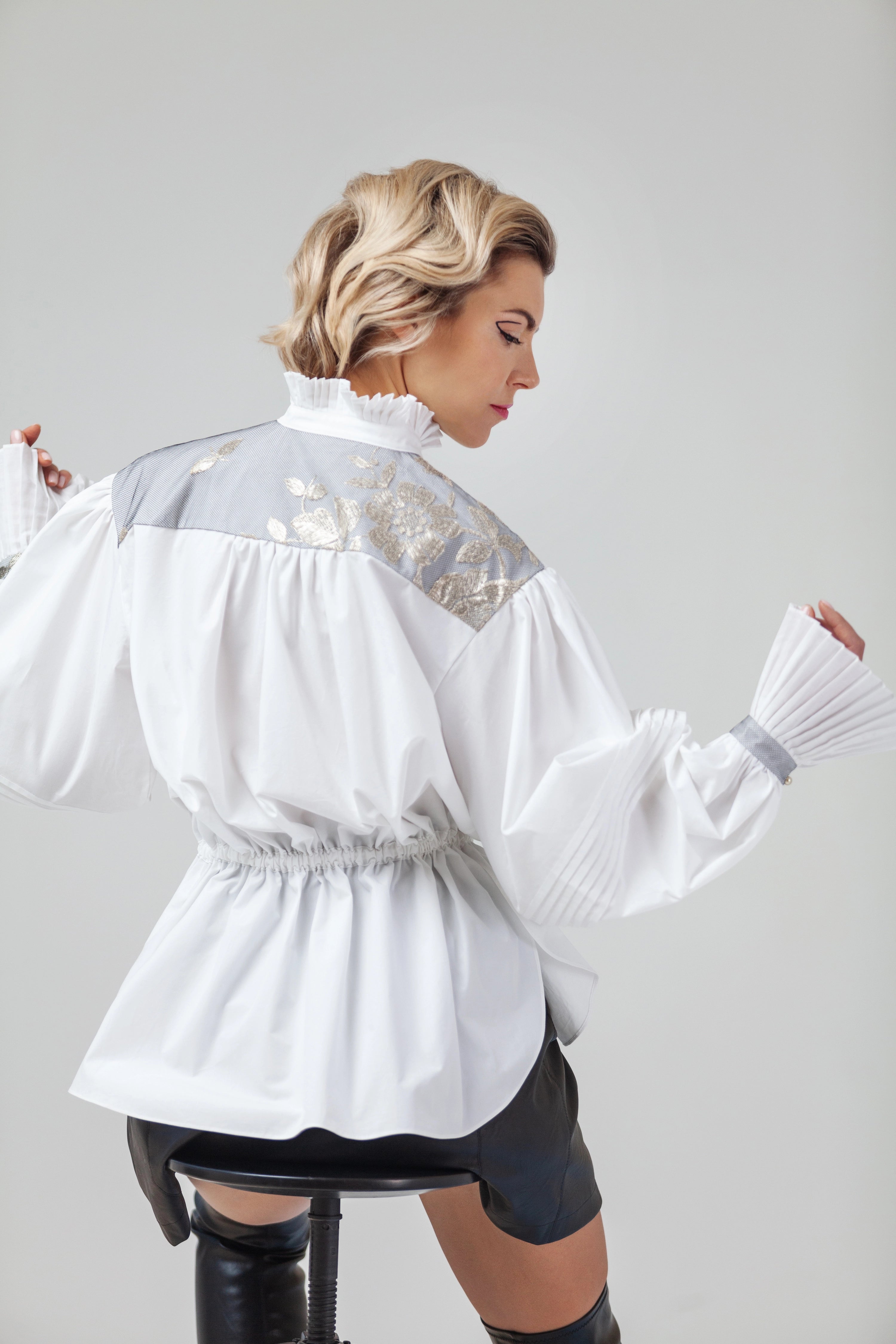 Woman wearing Blanc de Pouvoir from Mimaussy Paris, white blouse with sheer panels on plain background, studio setting