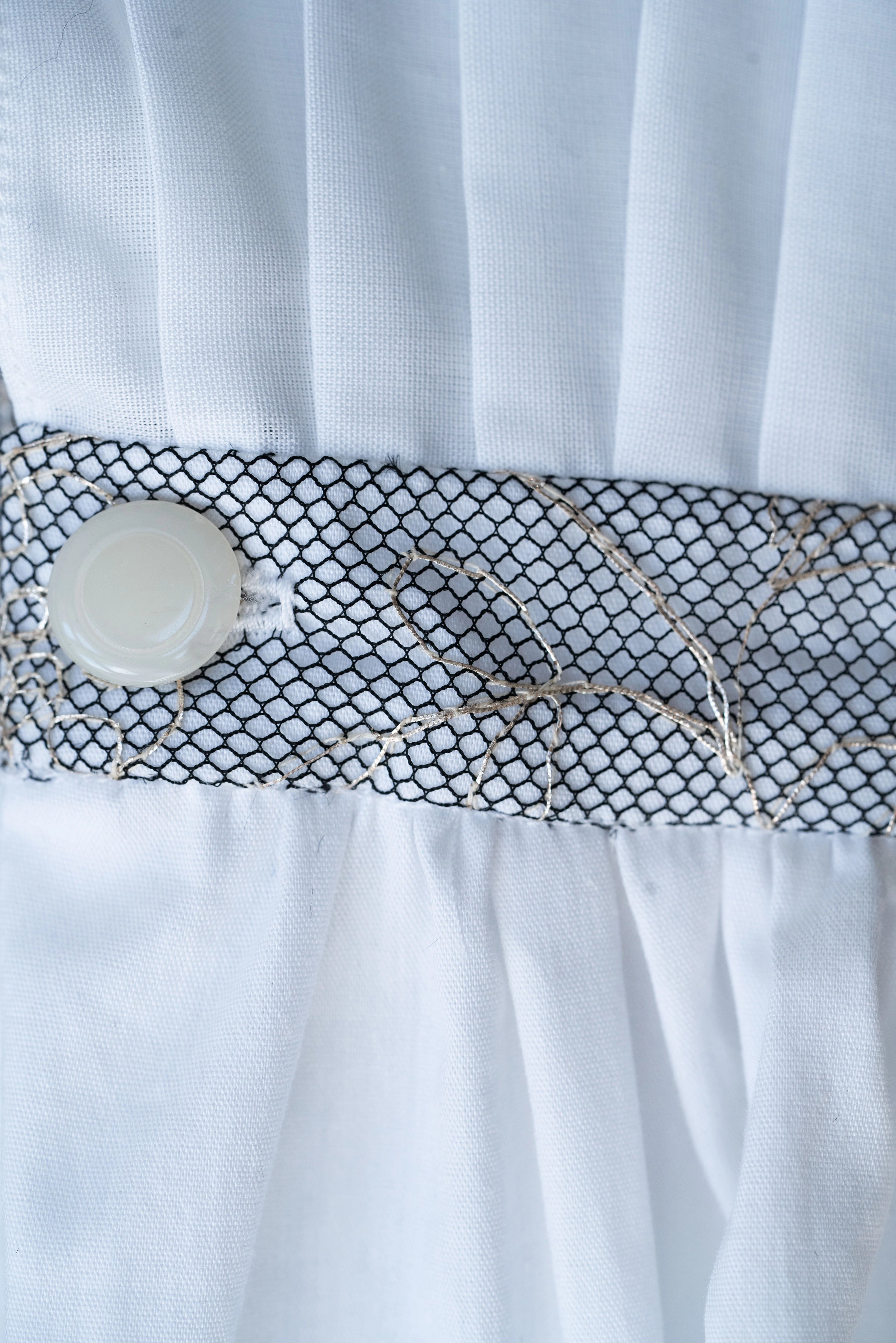 Woman wearing Blanc de Pouvoir from Mimaussy Paris, close-up of white dress with decorative belt featuring flower and chain details