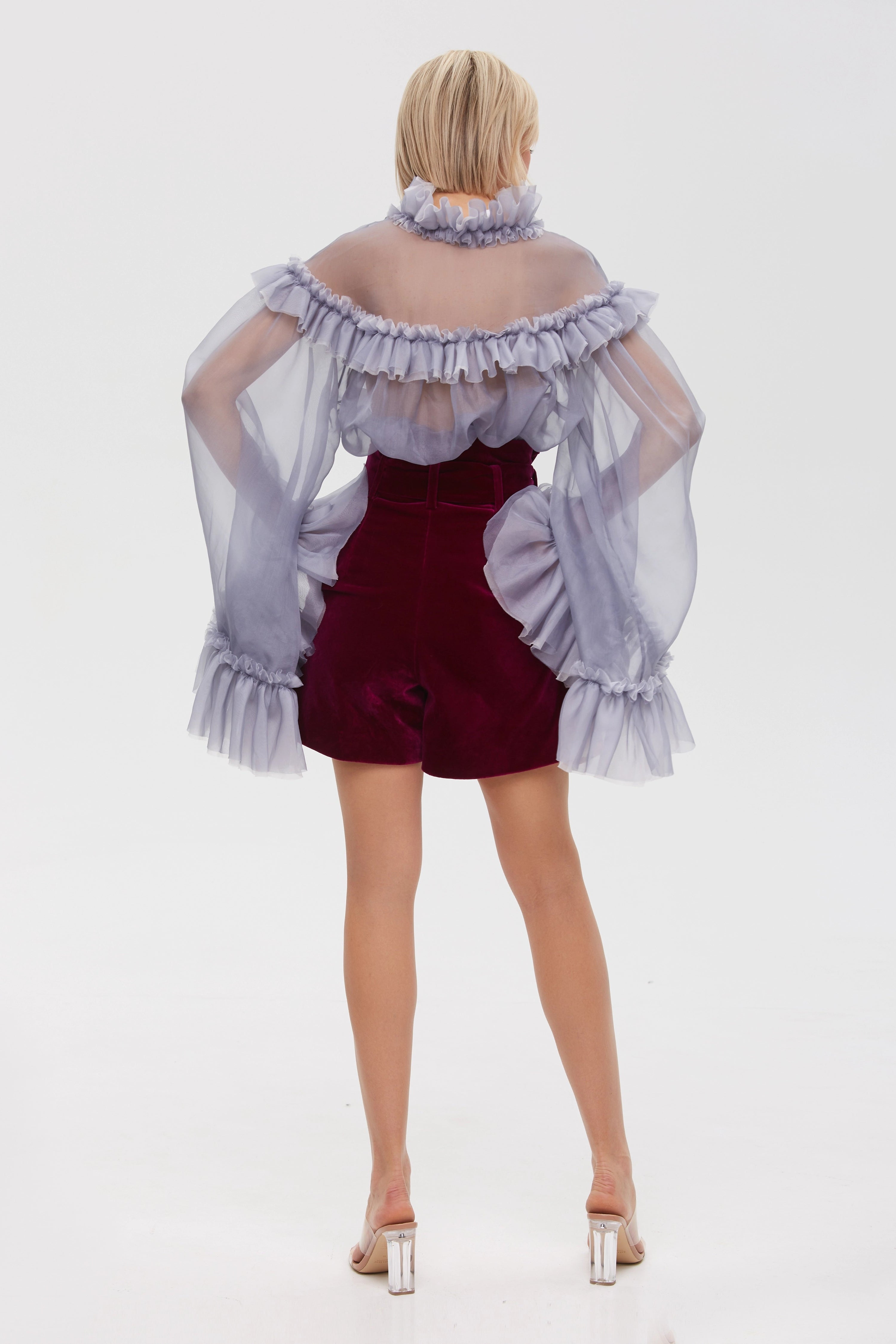 Woman wearing Burgundy Icon Shorts from Mimaussy Paris, full-length back view with off-shoulder ruffled top against a plain white studio background