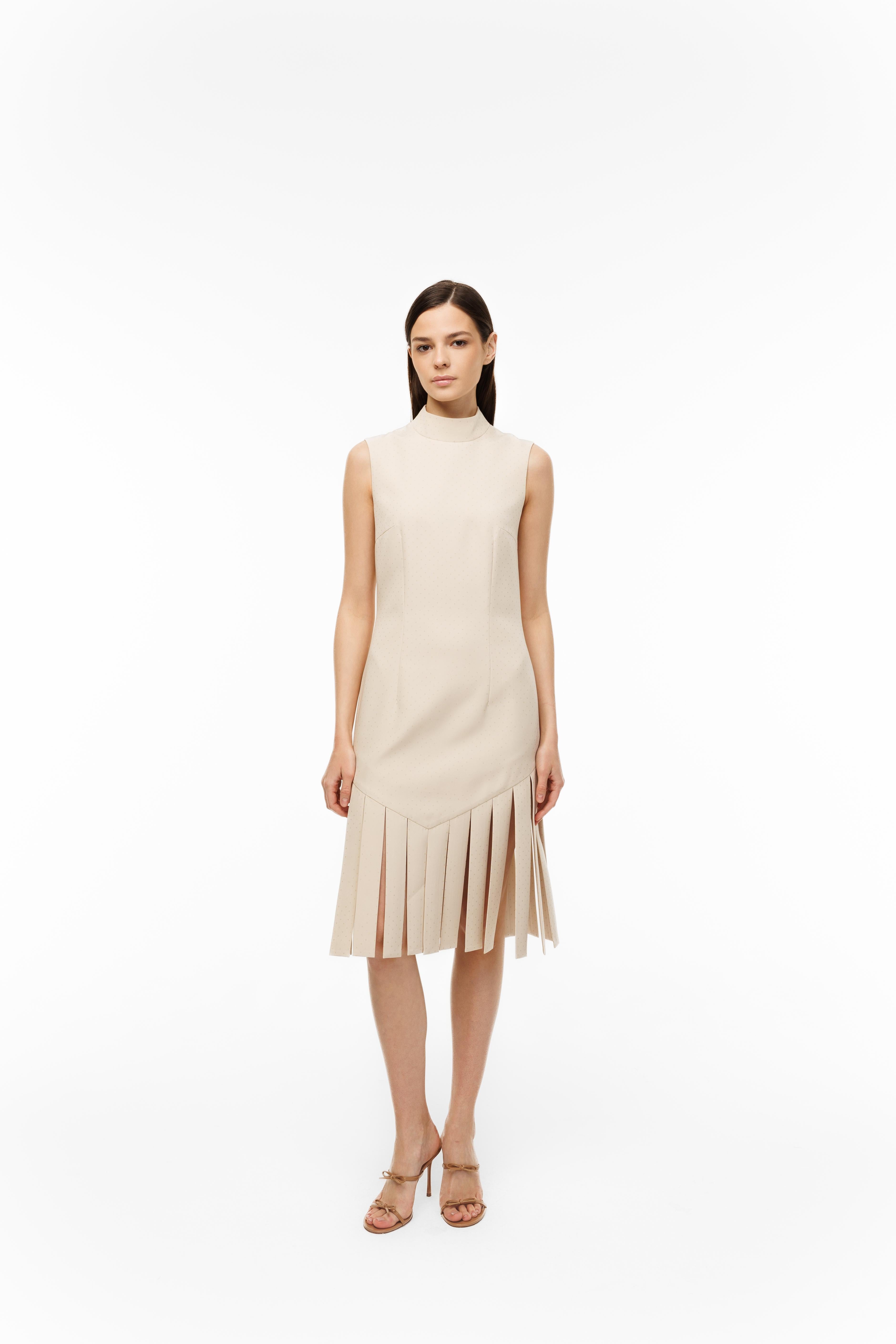 Woman wearing a beige sleeveless dress with fringe details on a white background