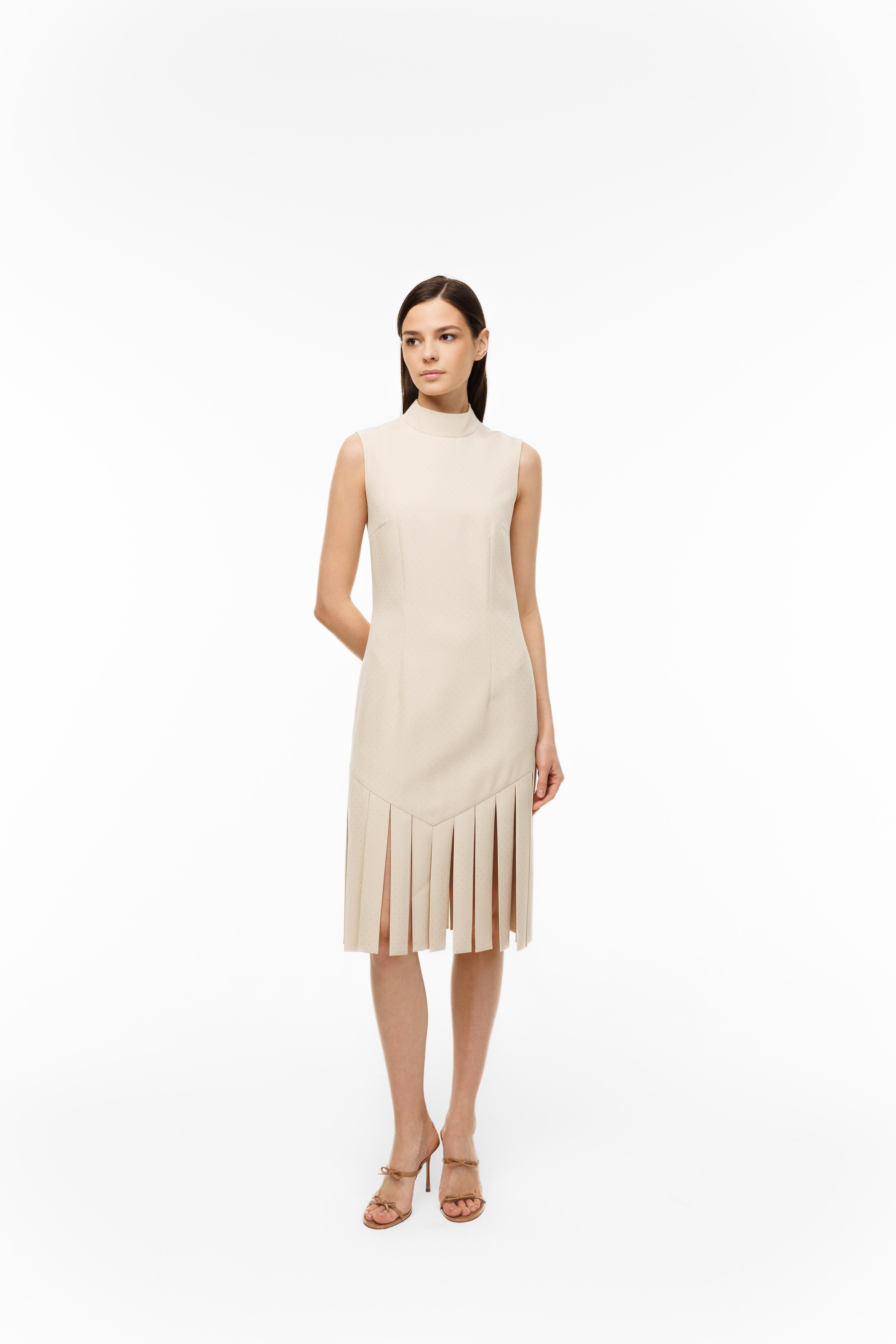 Woman wearing a beige sleeveless dress with fringe details on a white background