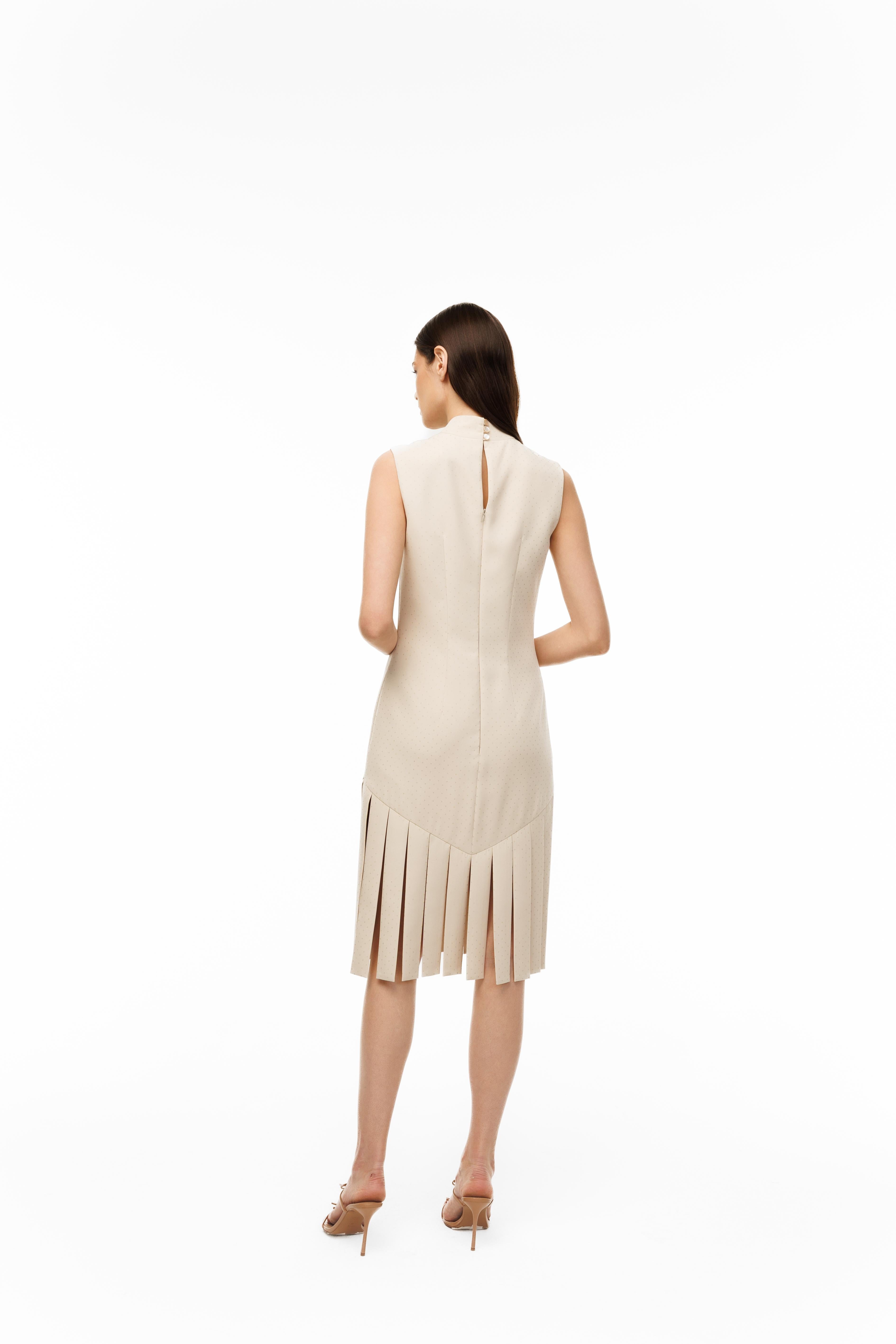 Woman wearing a beige dress with a slit back on a white background