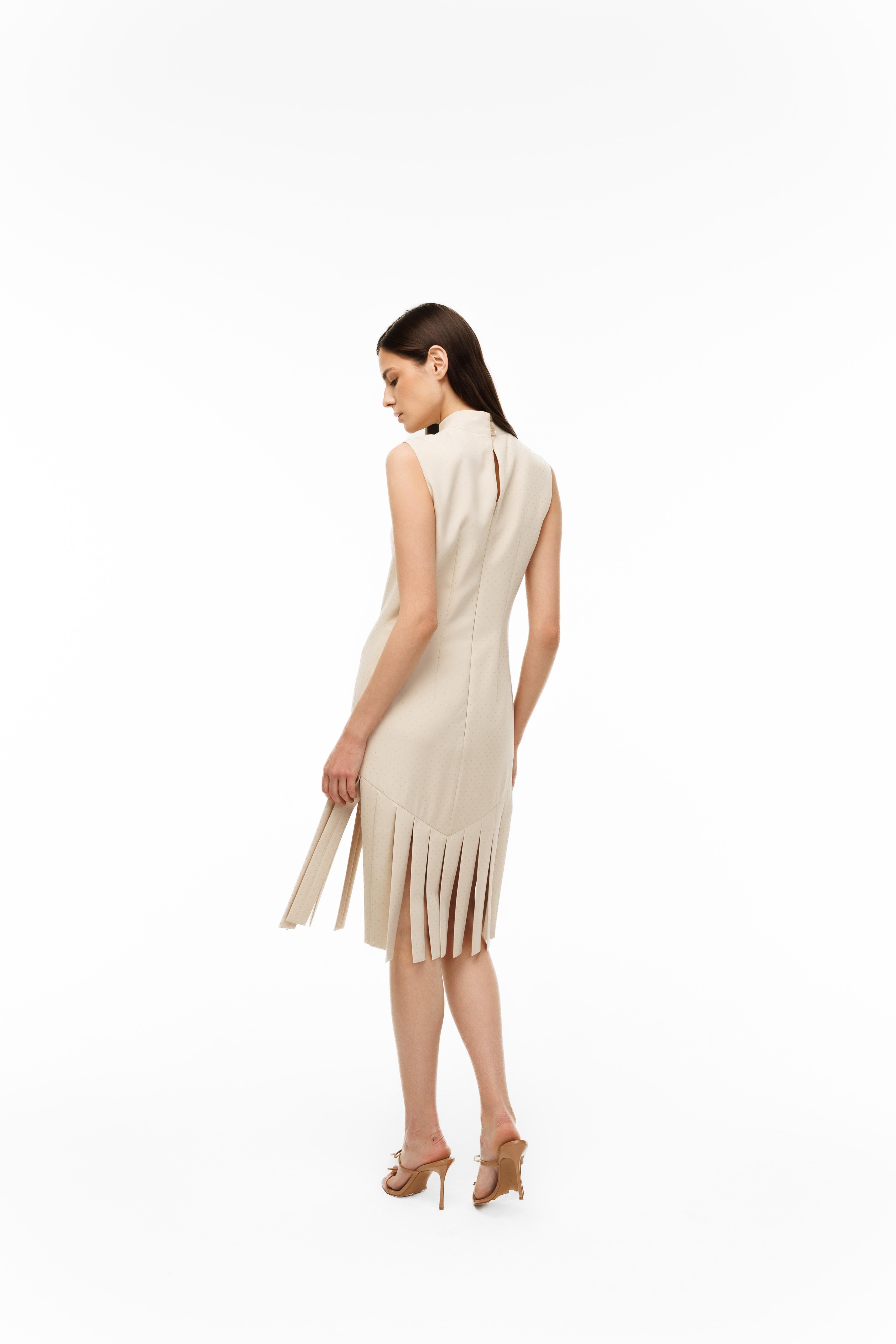 Woman wearing a beige dress with fringe details on a white background