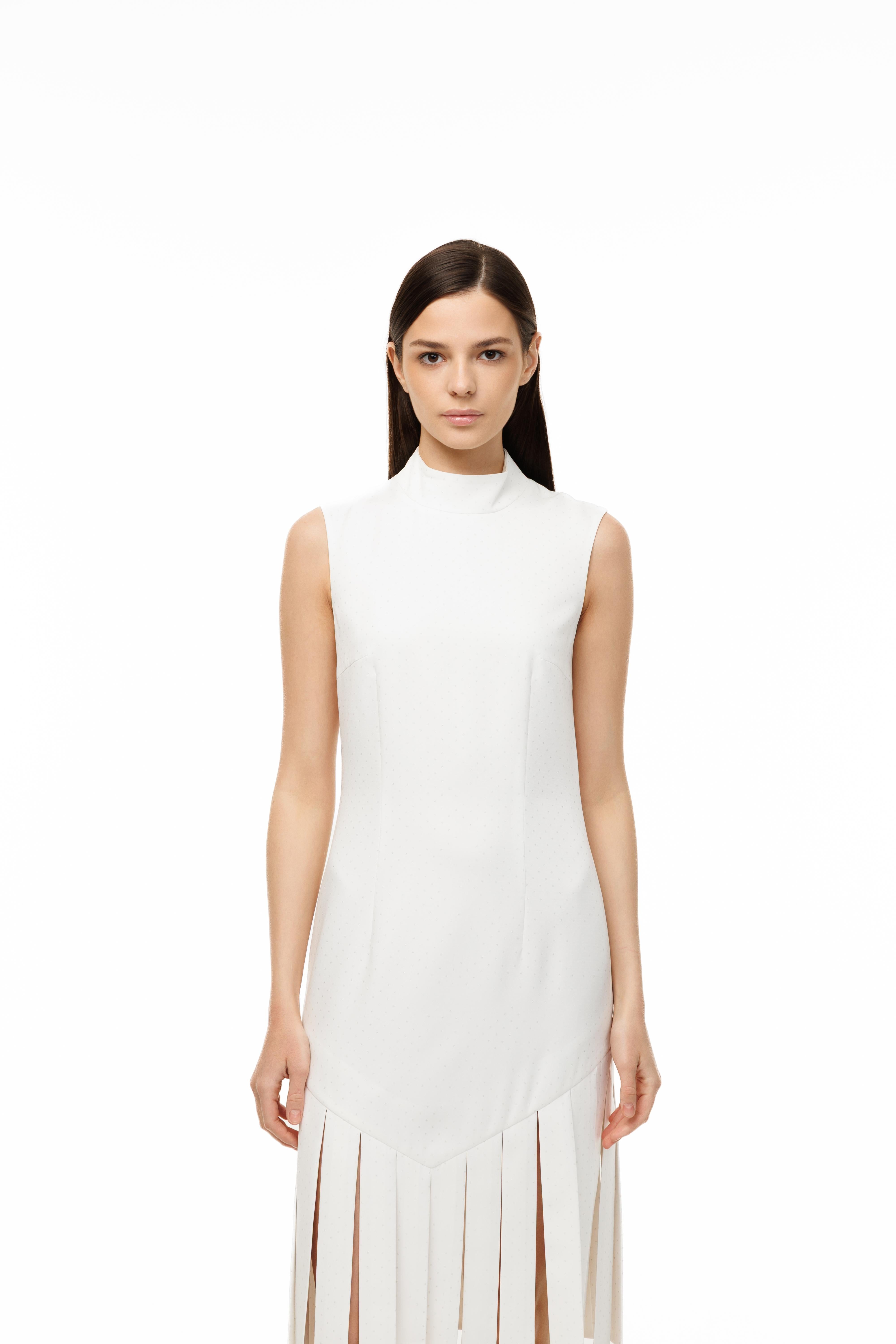 Woman wearing a white sleeveless dress with a high collar on a white background