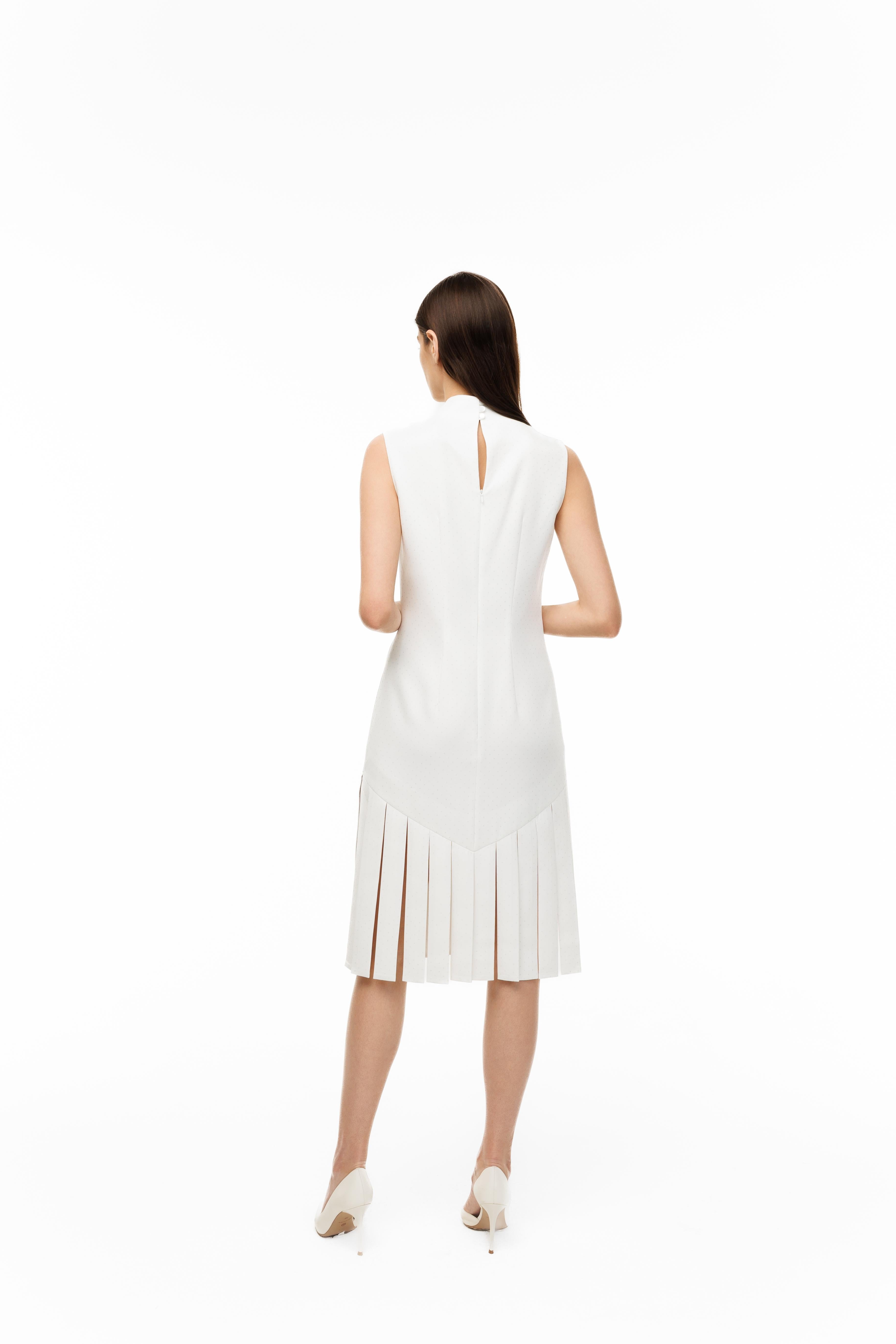 Woman wearing a white dress with pleated details on a white background