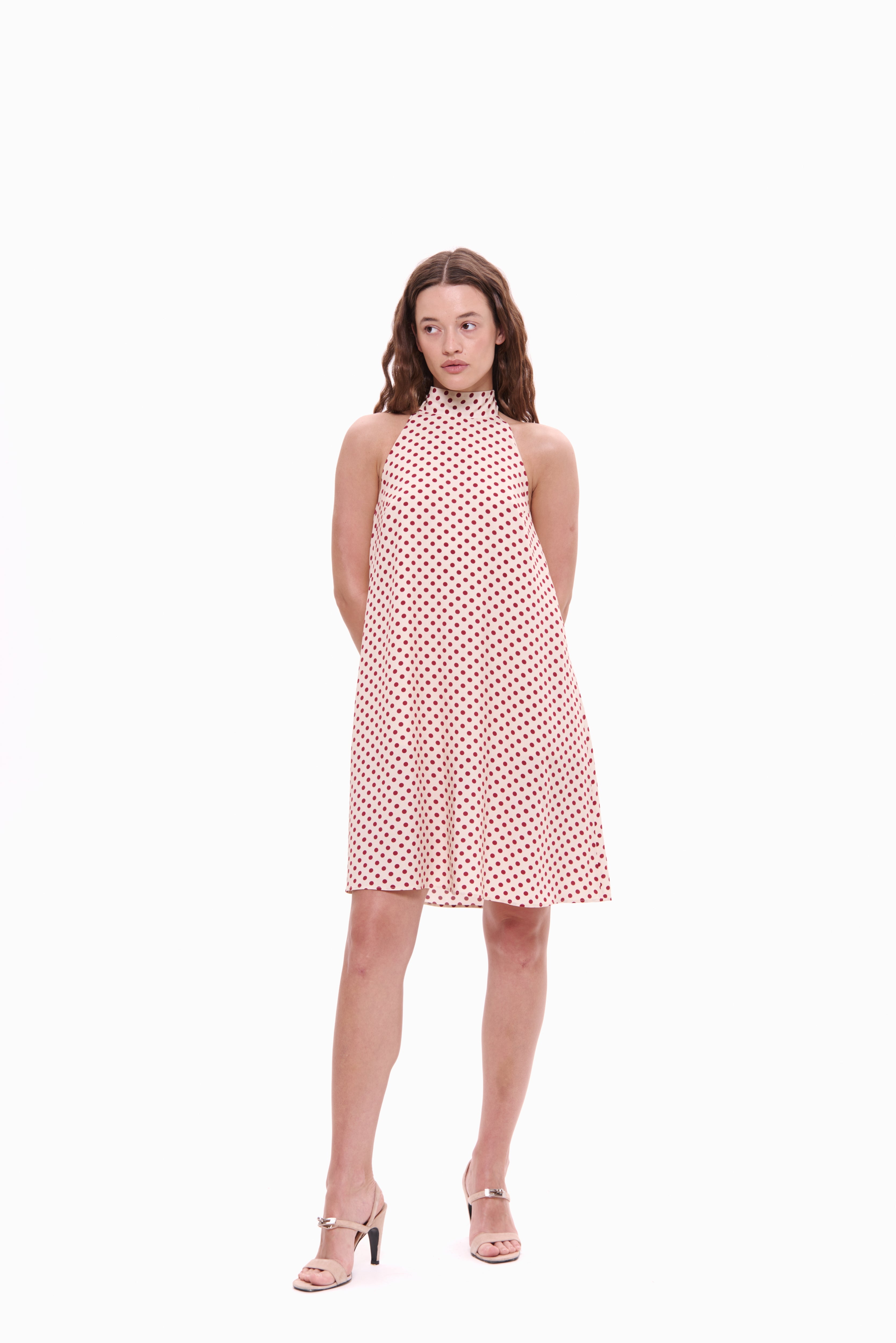 Woman wearing a pink polka dot dress on a white background