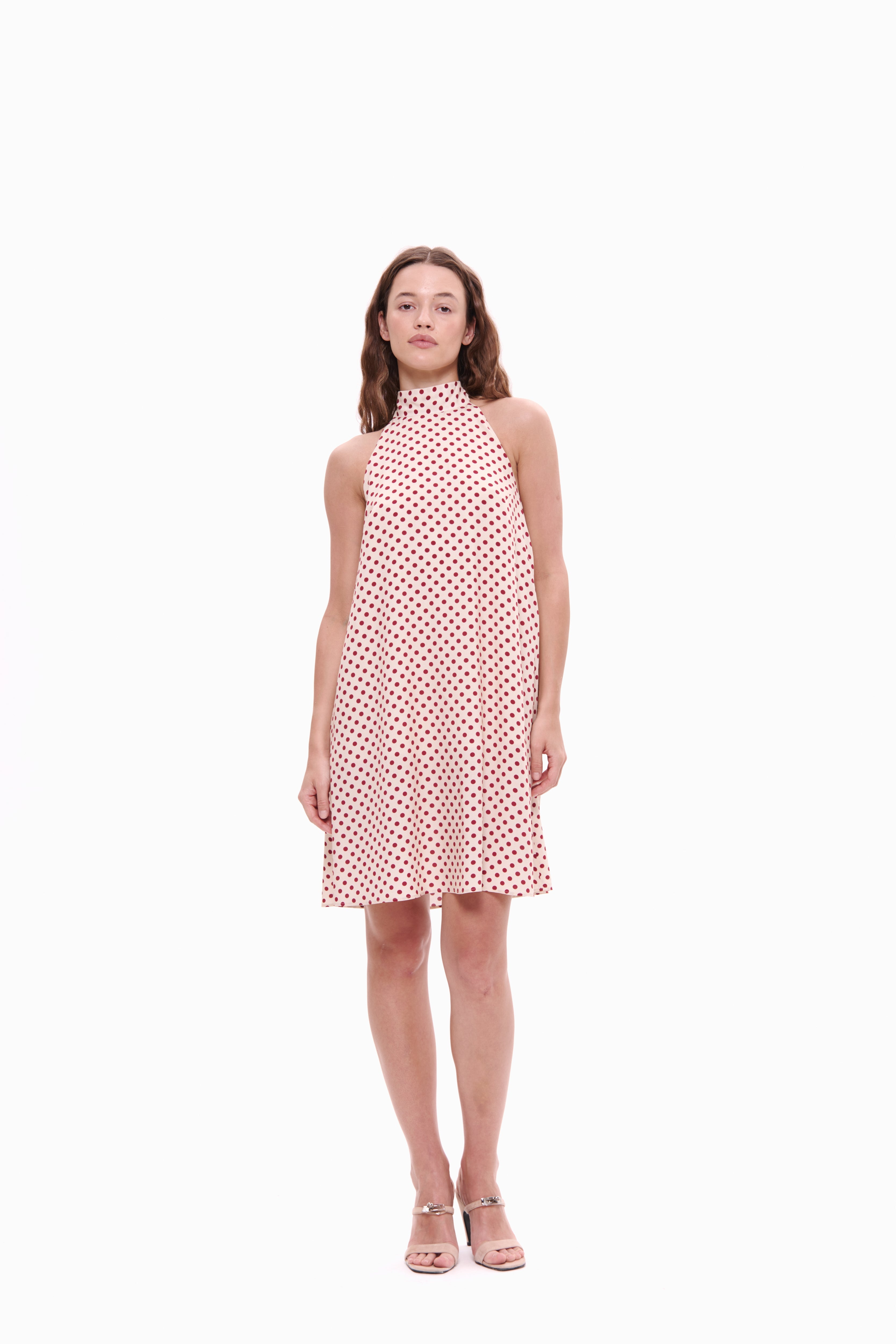 Woman wearing a pink polka dot dress on a white background
