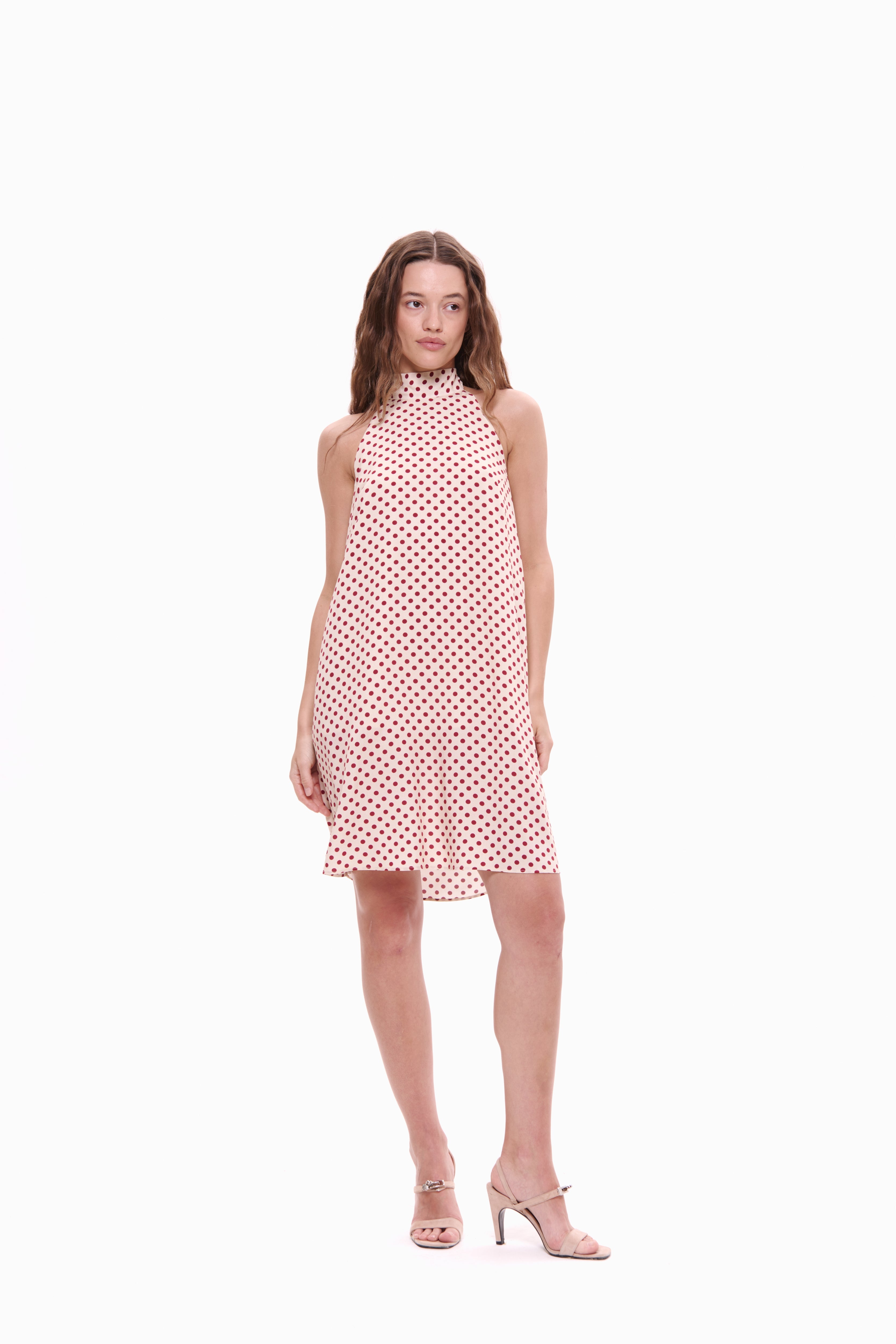 Woman wearing a pink polka dot dress on a white background