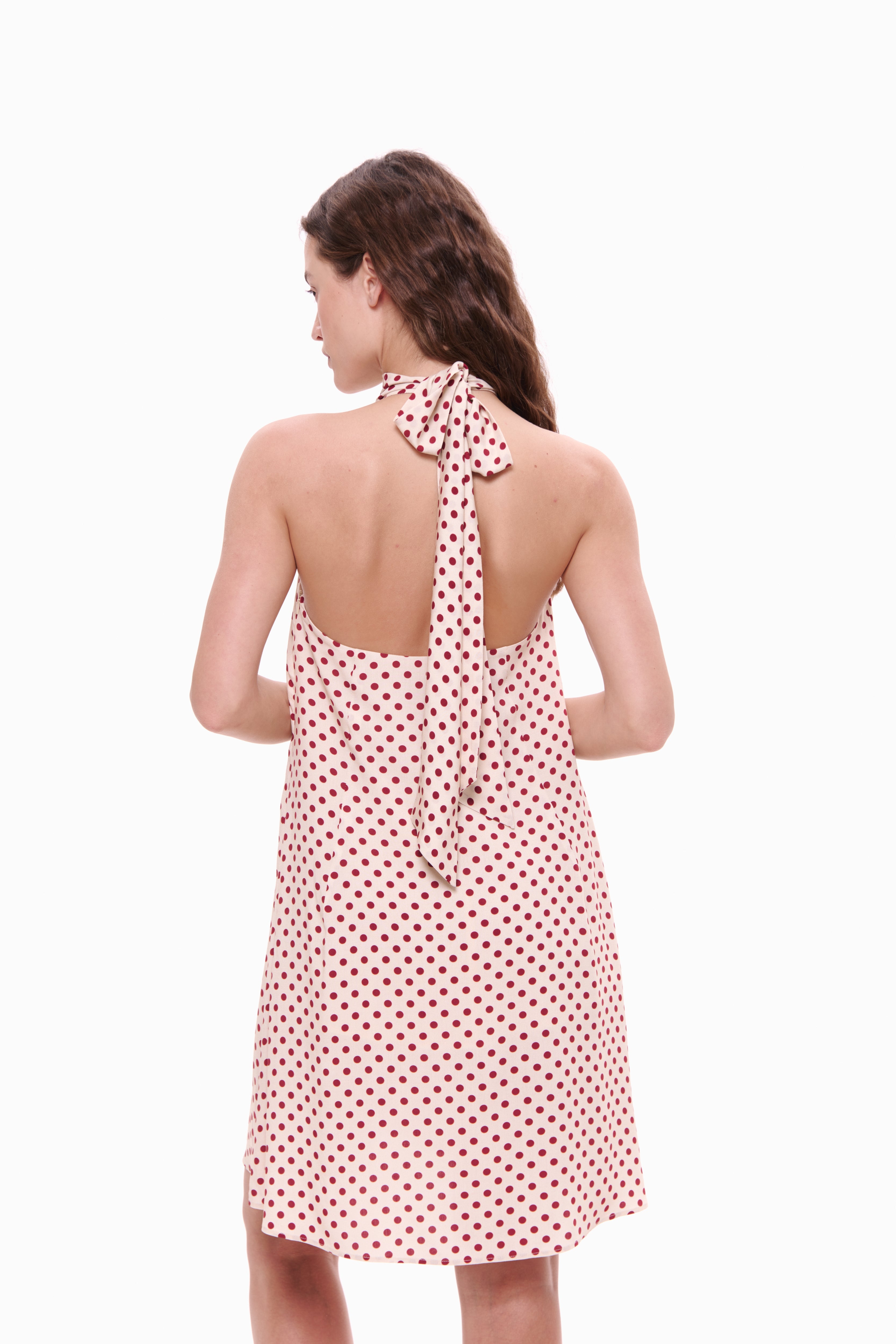 Woman wearing a polka dot dress with a halter neck design on a white background