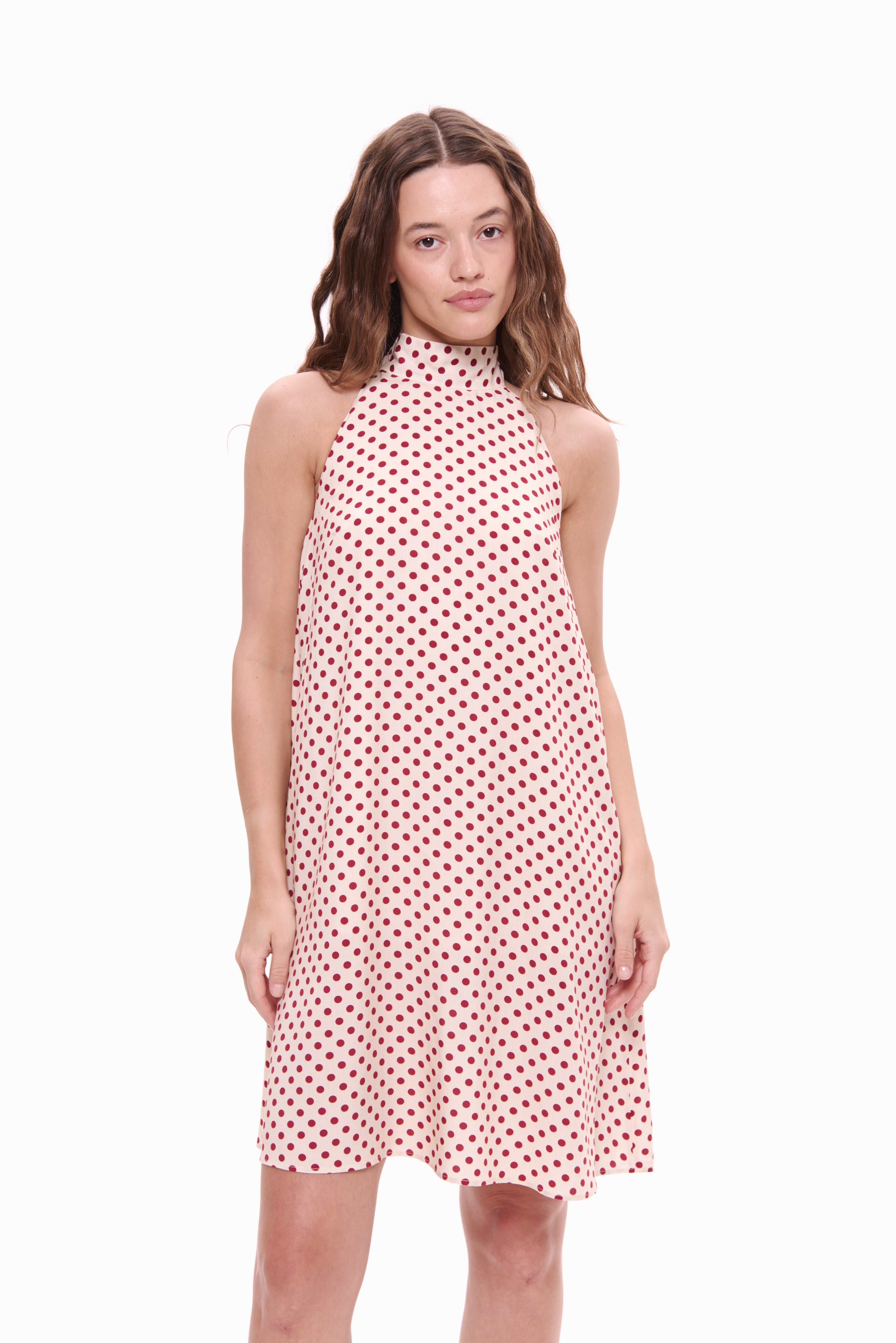 Woman wearing a pink dress with red polka dots on a white background