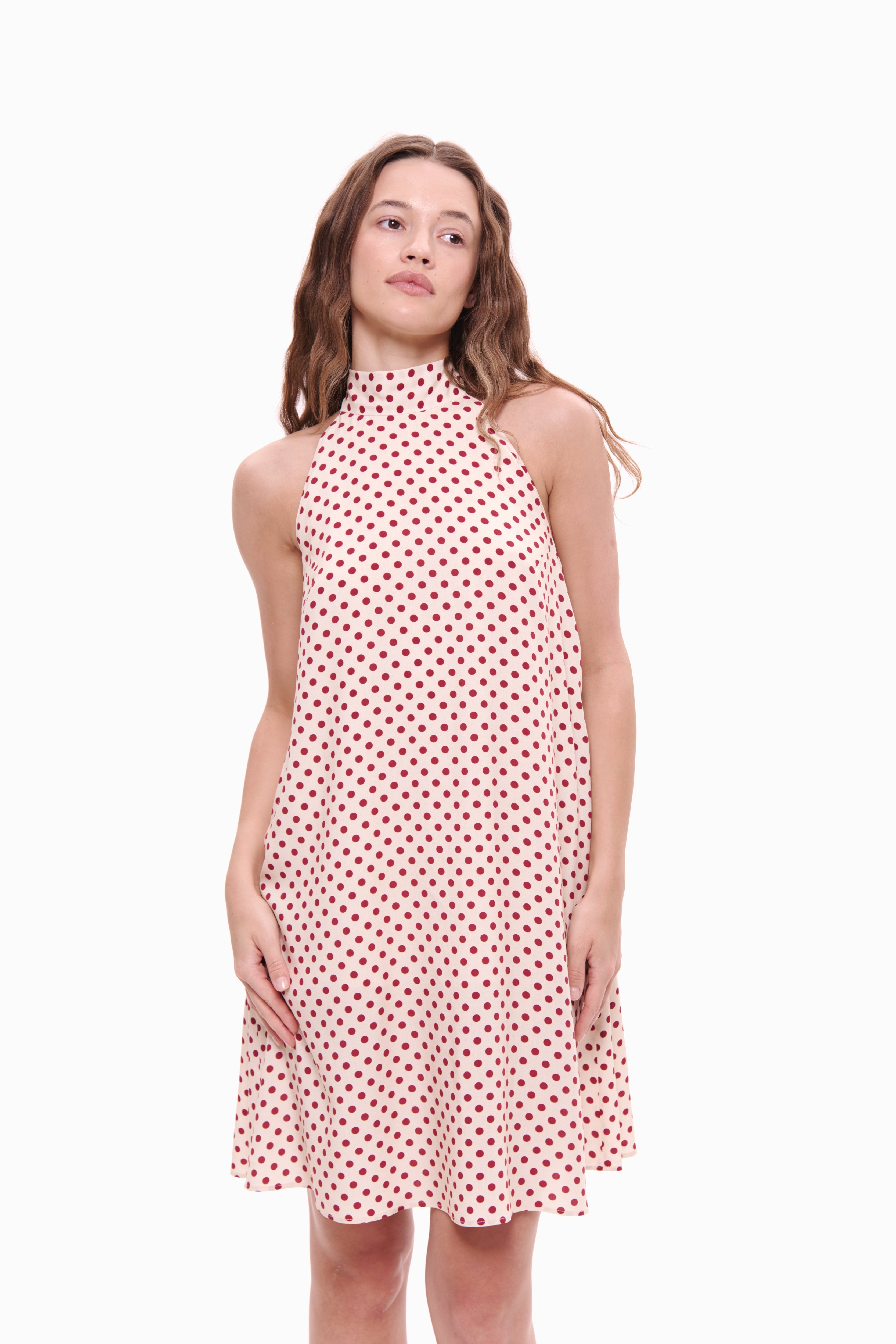 Woman wearing a red and white polka dot dress on a white background