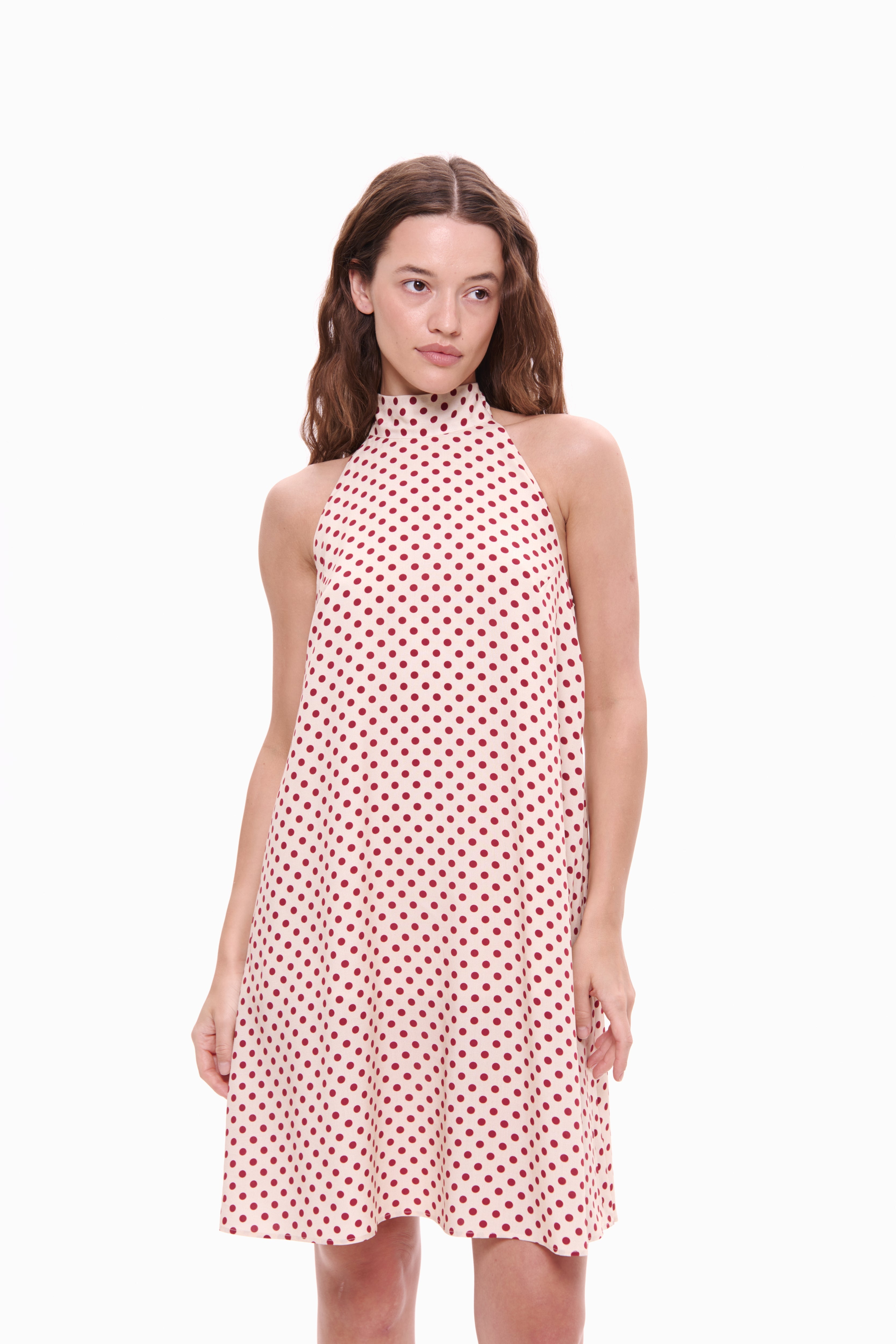 Woman wearing a red and white polka dot dress on a white background