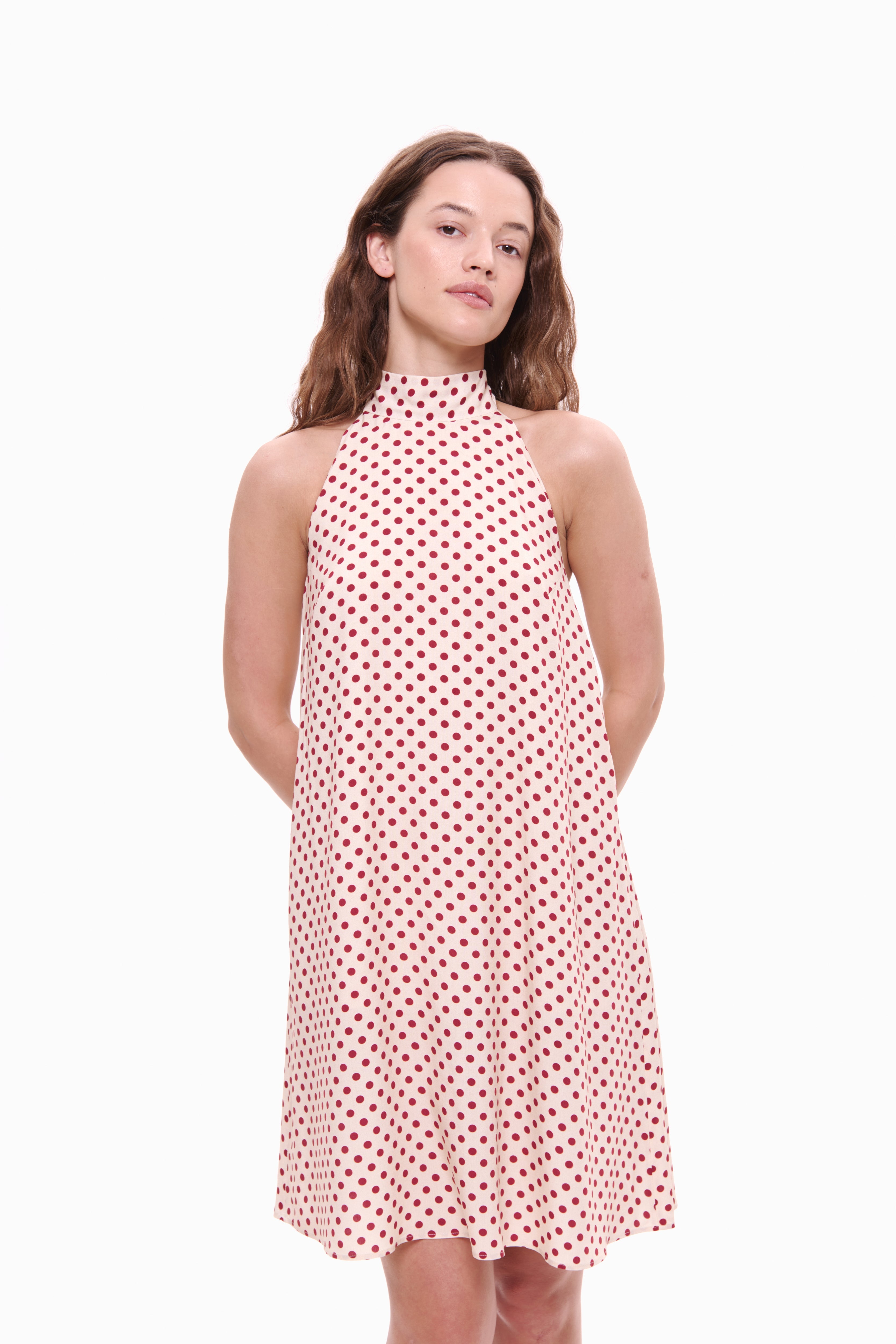 Woman wearing a red and white polka dot dress on a white background