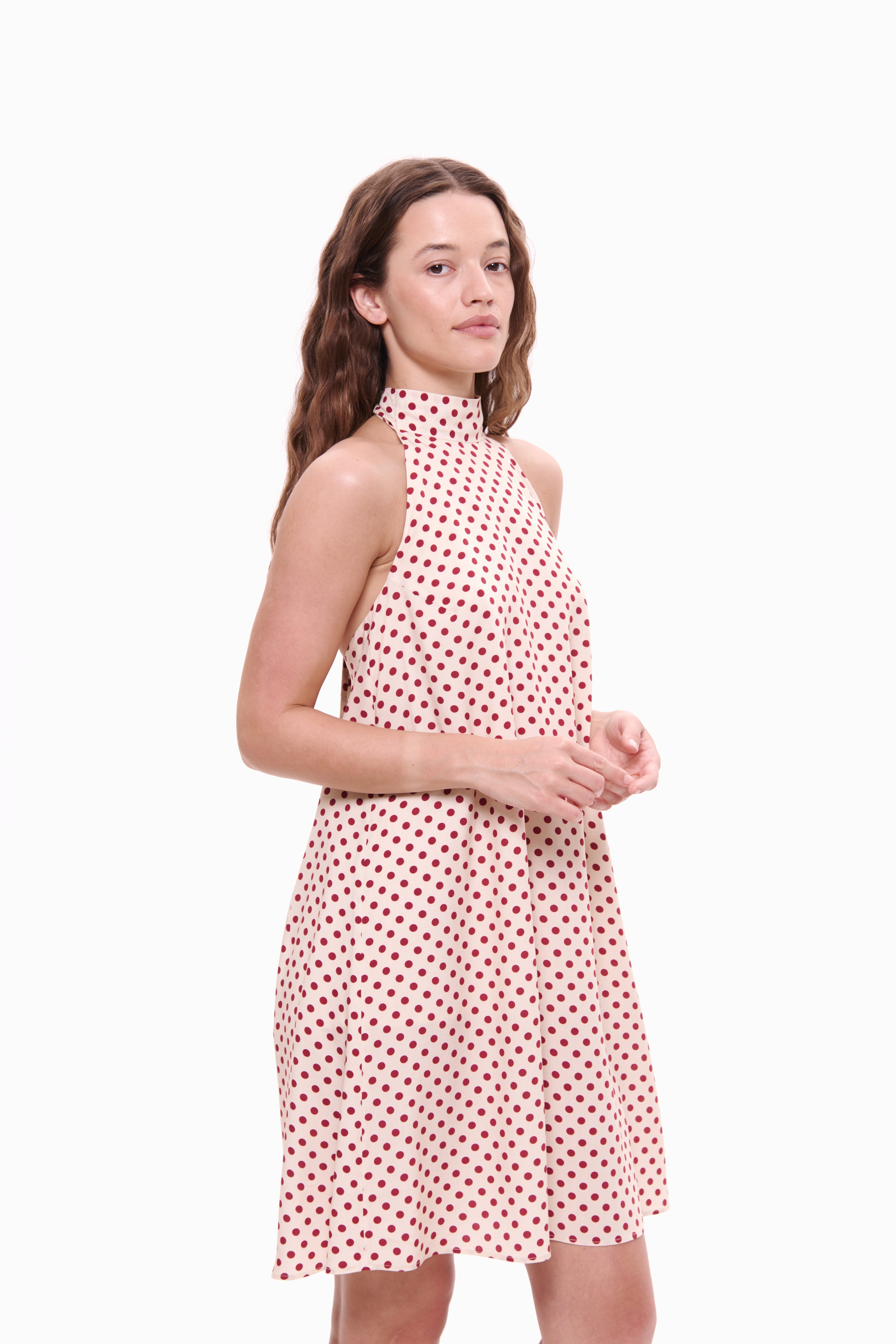 Woman wearing a red and white polka dot dress on a white background