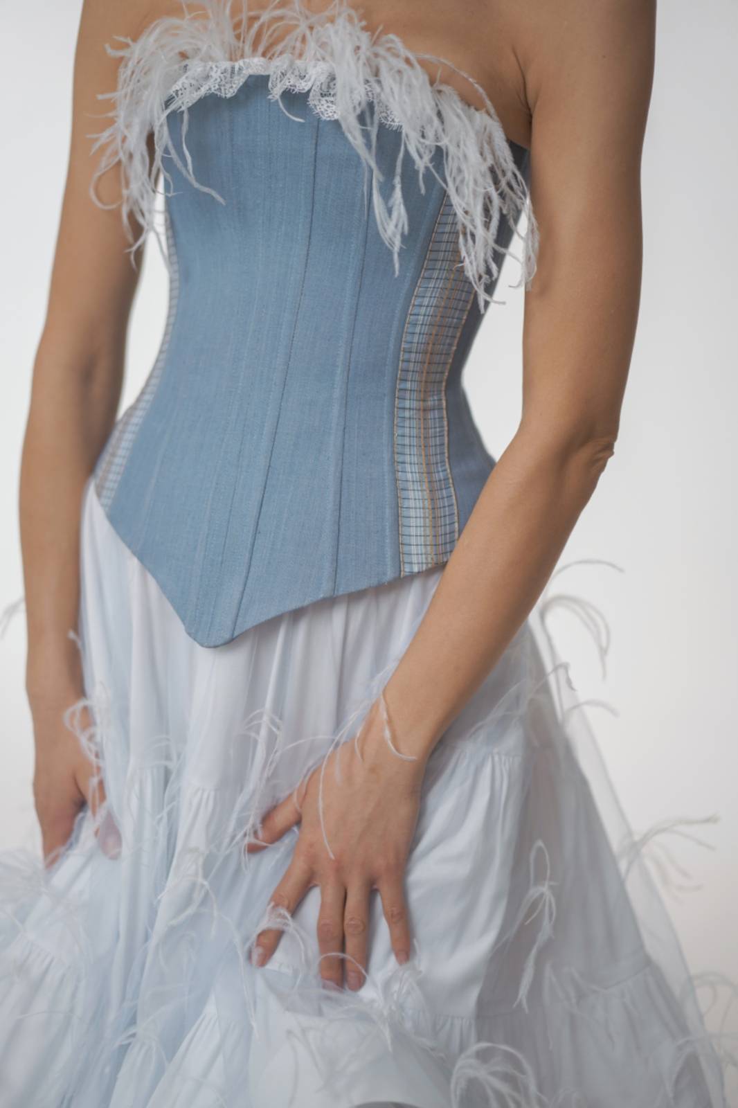 Blue corset with plaid pattern and white feathered details on a plain background