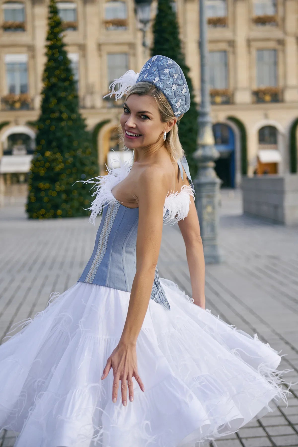 A woman in a blue denim corset dress and white hat, showcasing a stylish look from Mimaussy Paris.