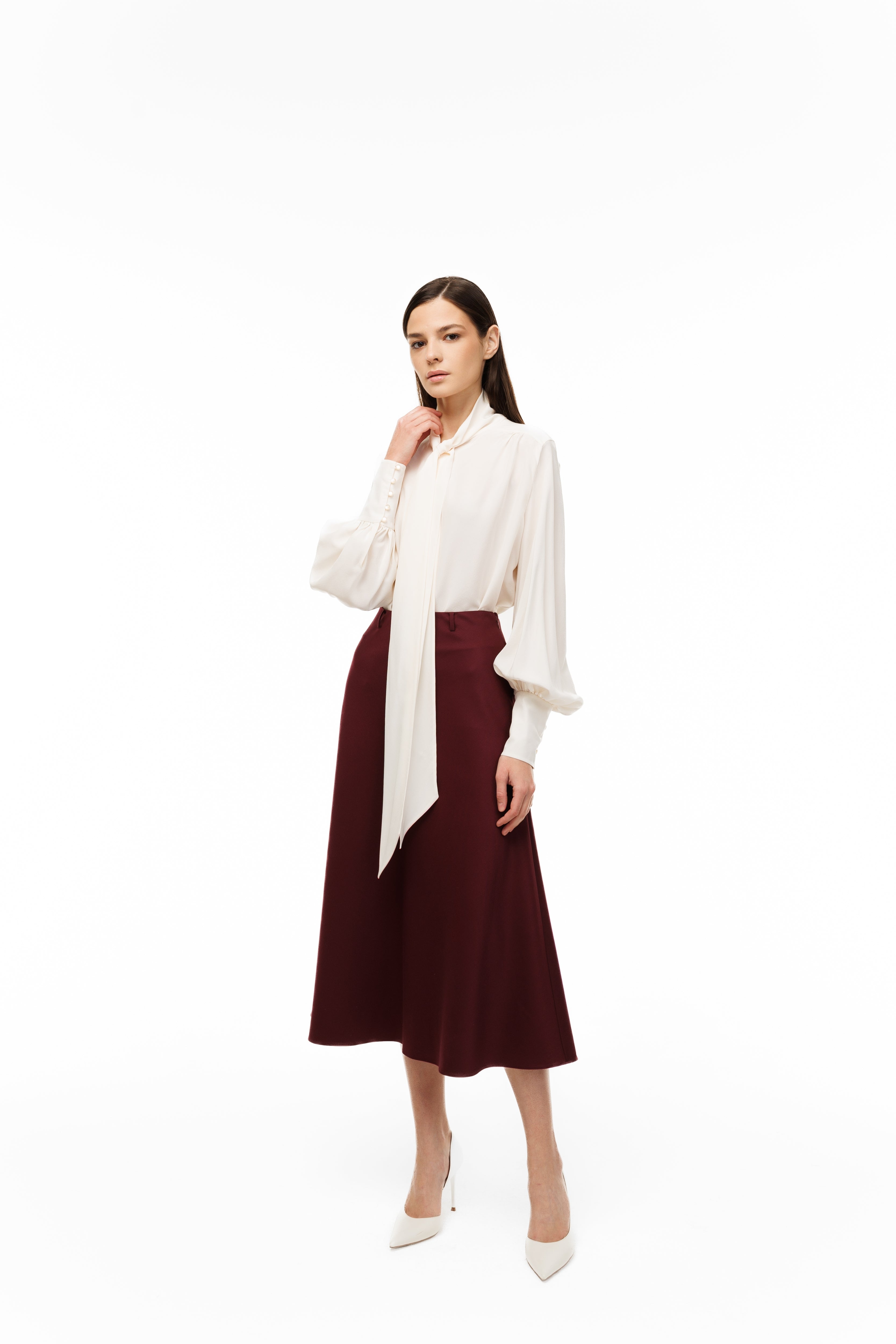 Woman wearing a white blouse and burgundy skirt on a white background