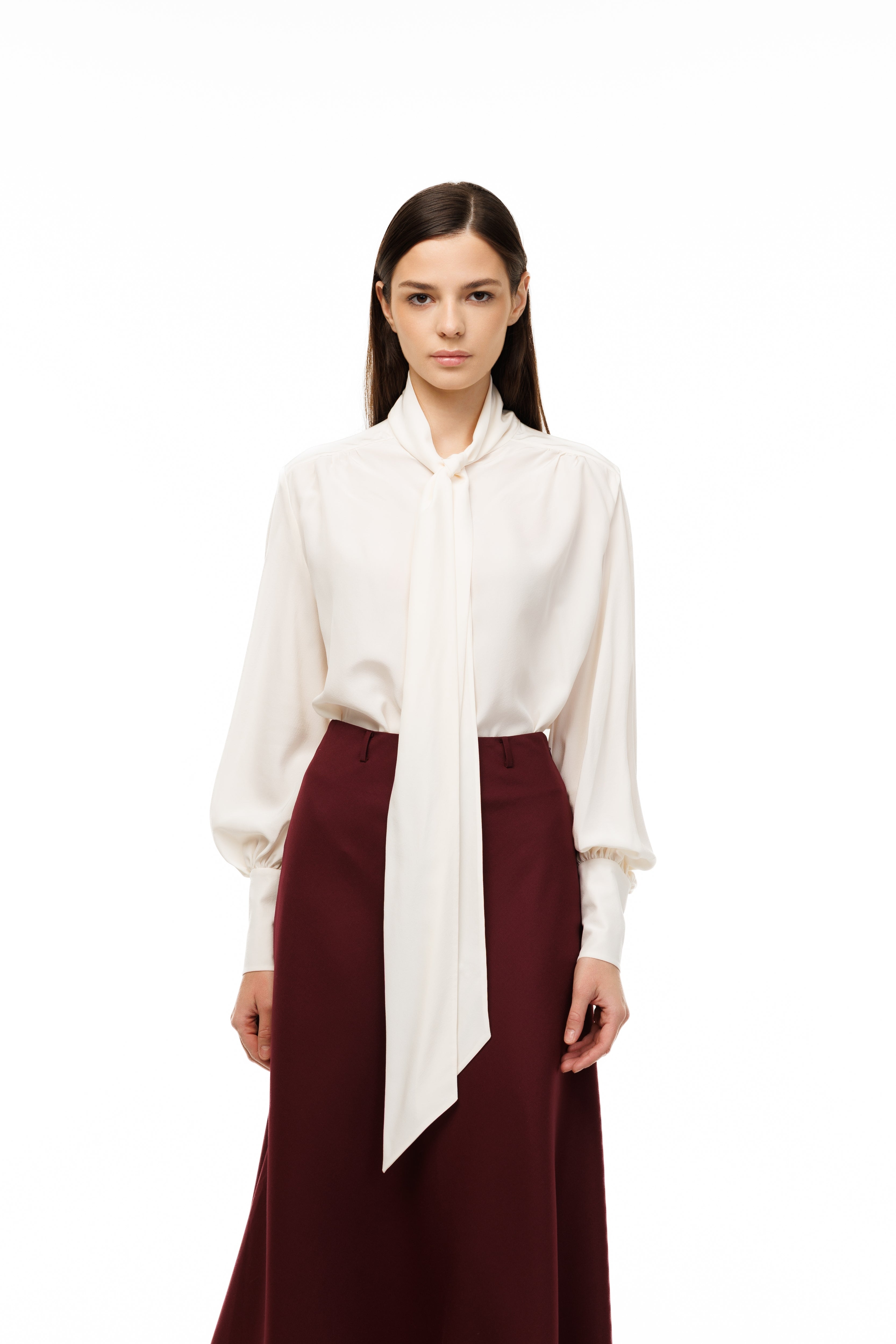 Woman wearing a white blouse and burgundy skirt on a white background