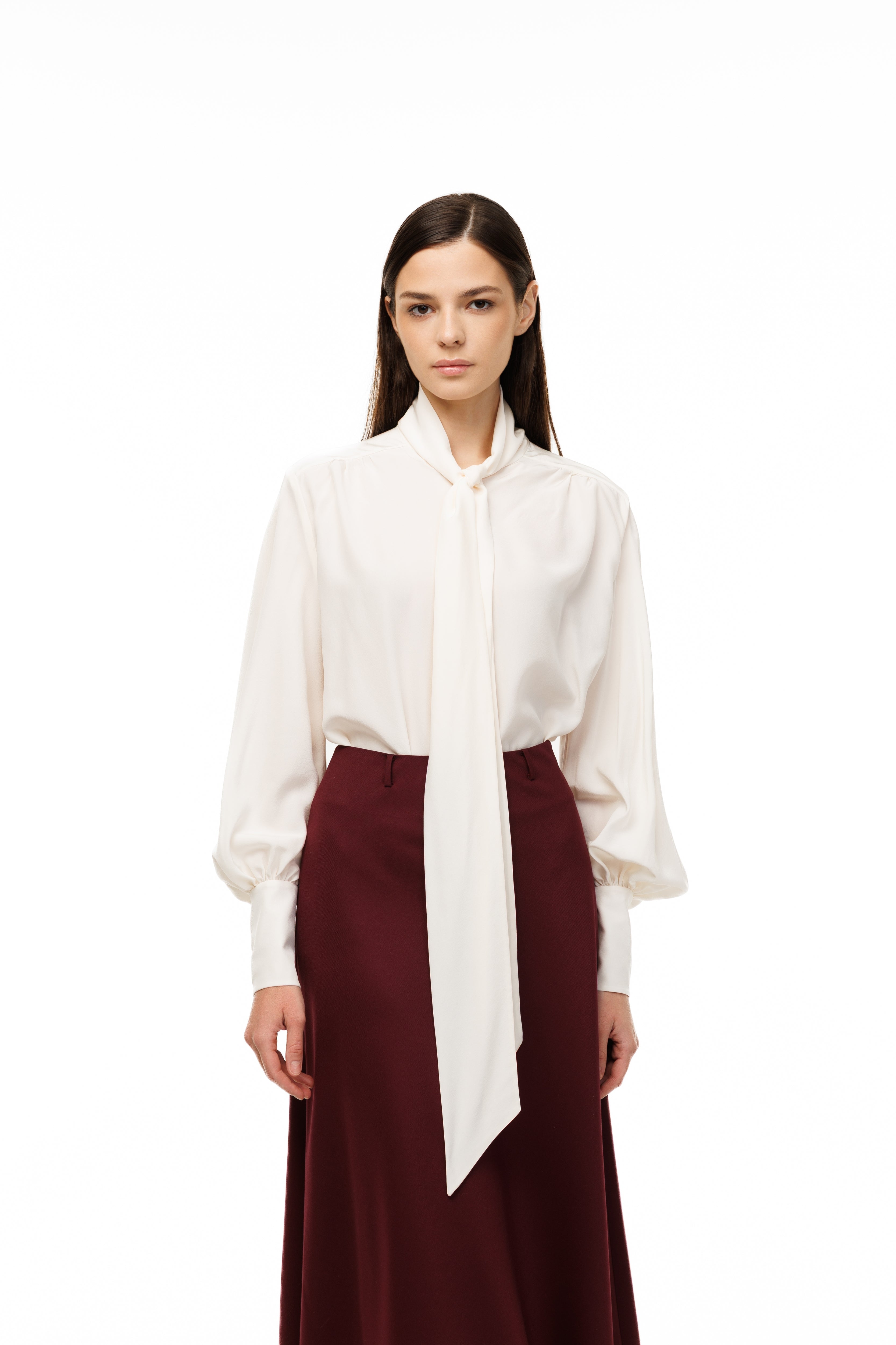 Woman wearing a white blouse and burgundy skirt on a white background