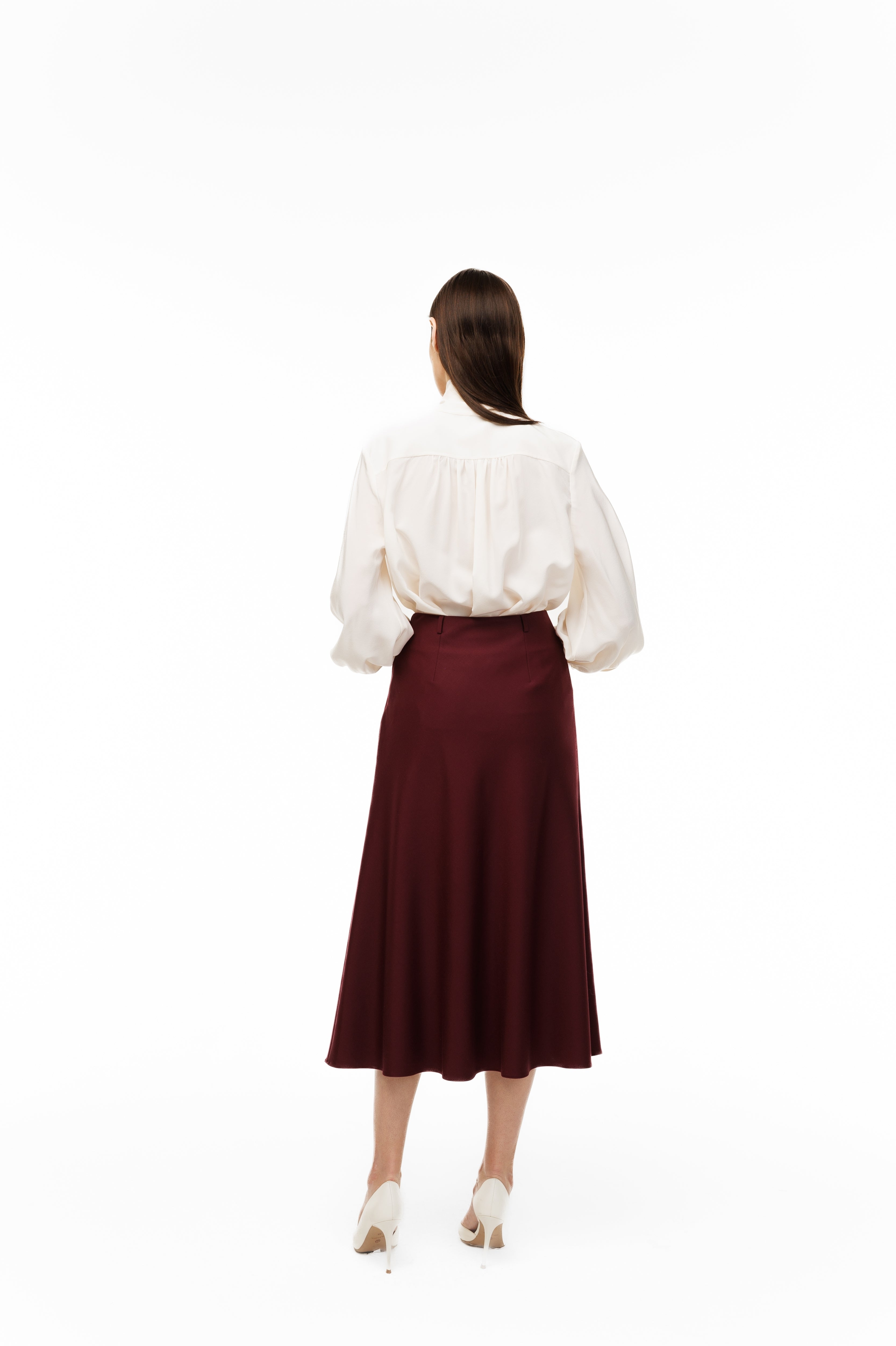 Woman wearing a white blouse and burgundy skirt on a white background