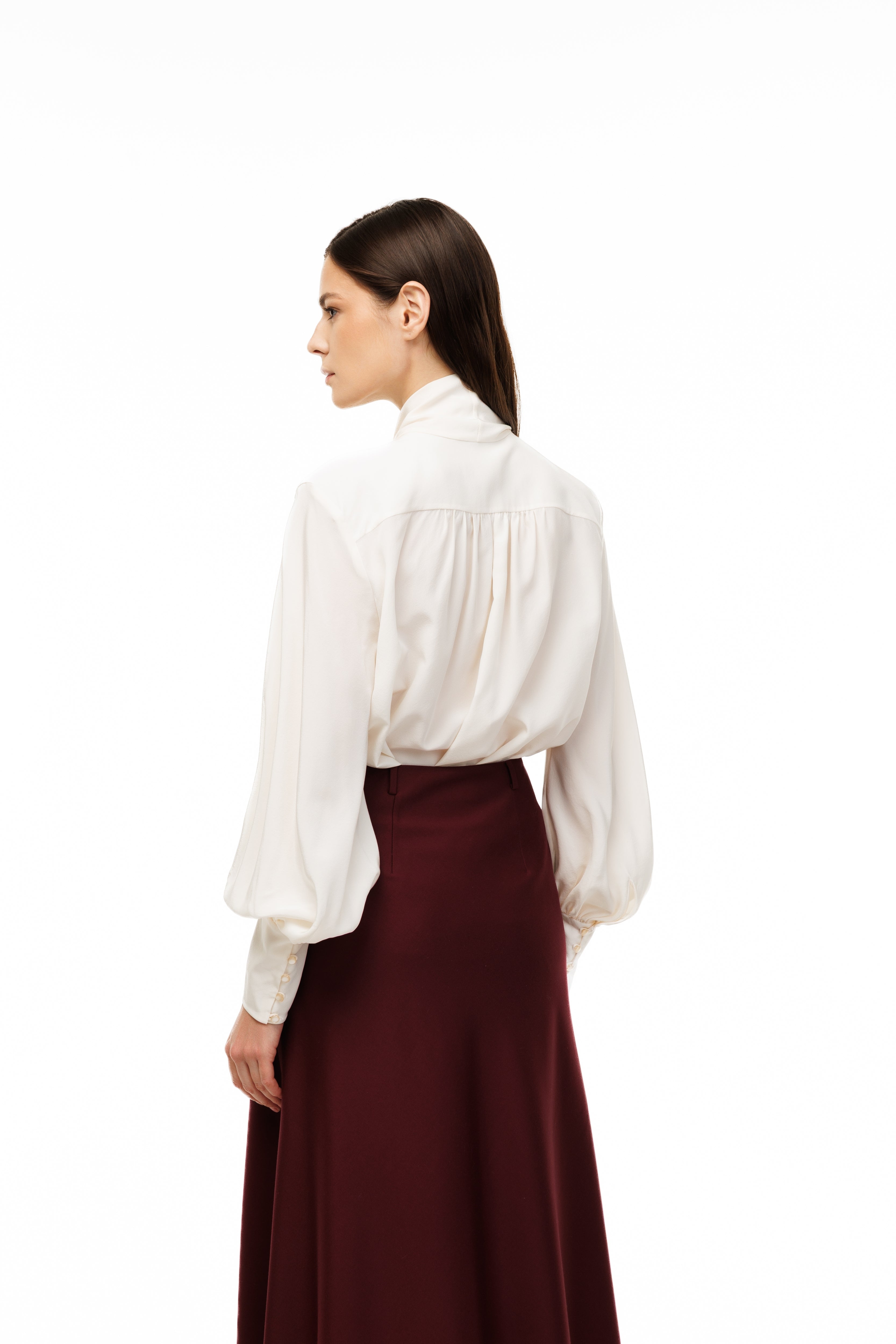 Woman wearing a white blouse and burgundy skirt on a white background