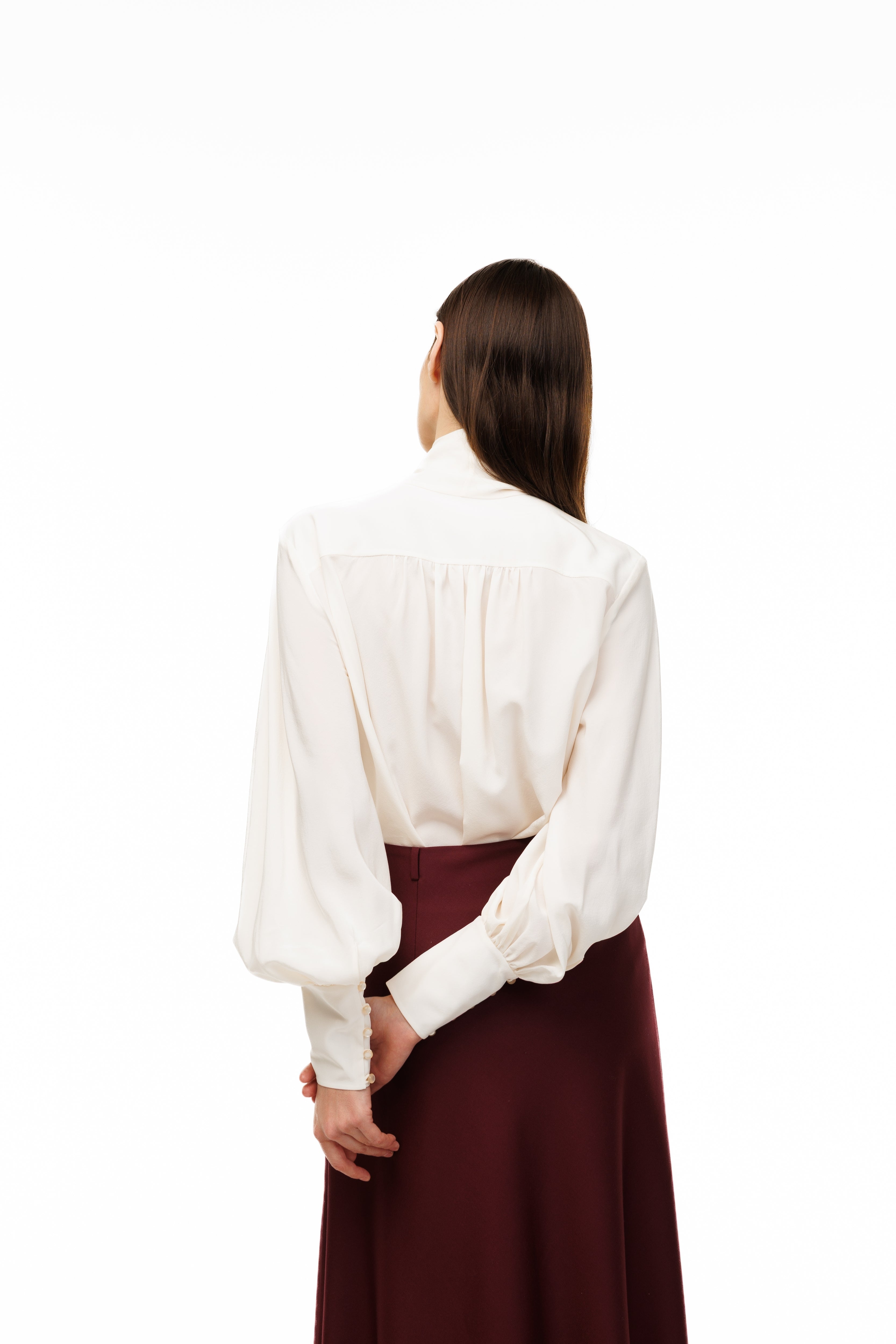 Woman wearing a white blouse and maroon skirt on a white background