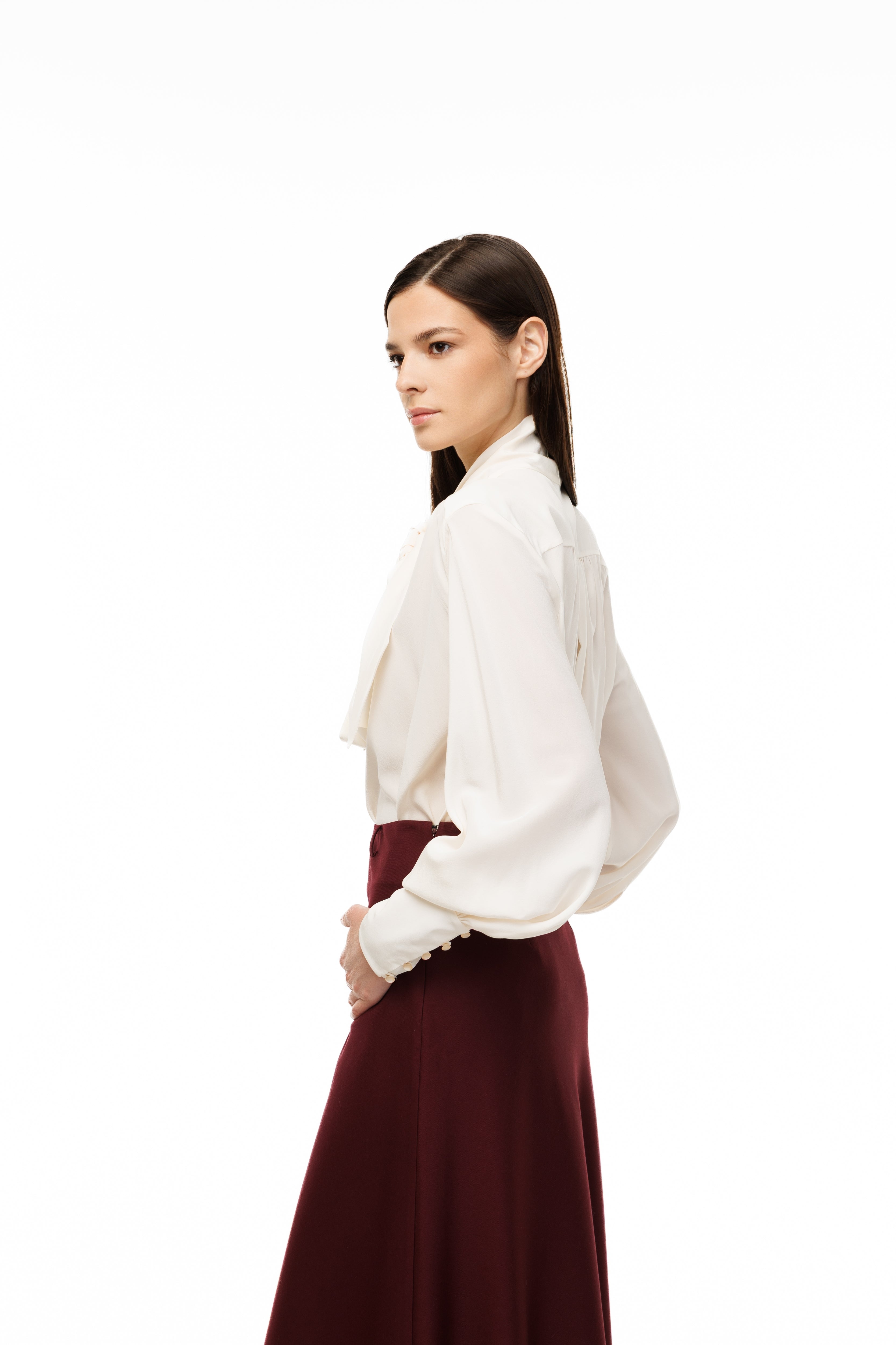Woman wearing a white blouse and burgundy skirt on a white background