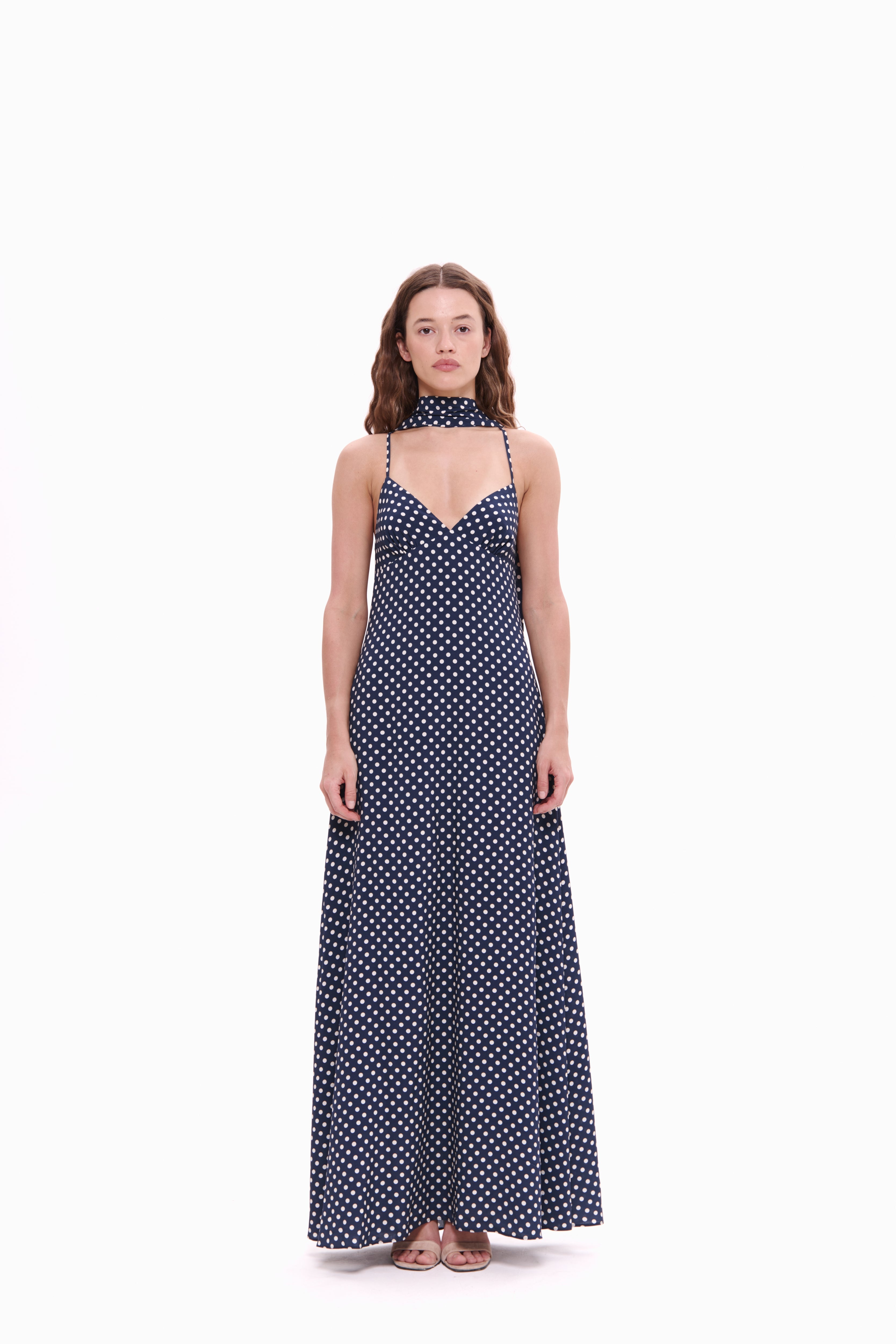 Woman wearing a navy blue polka dot dress on a white background