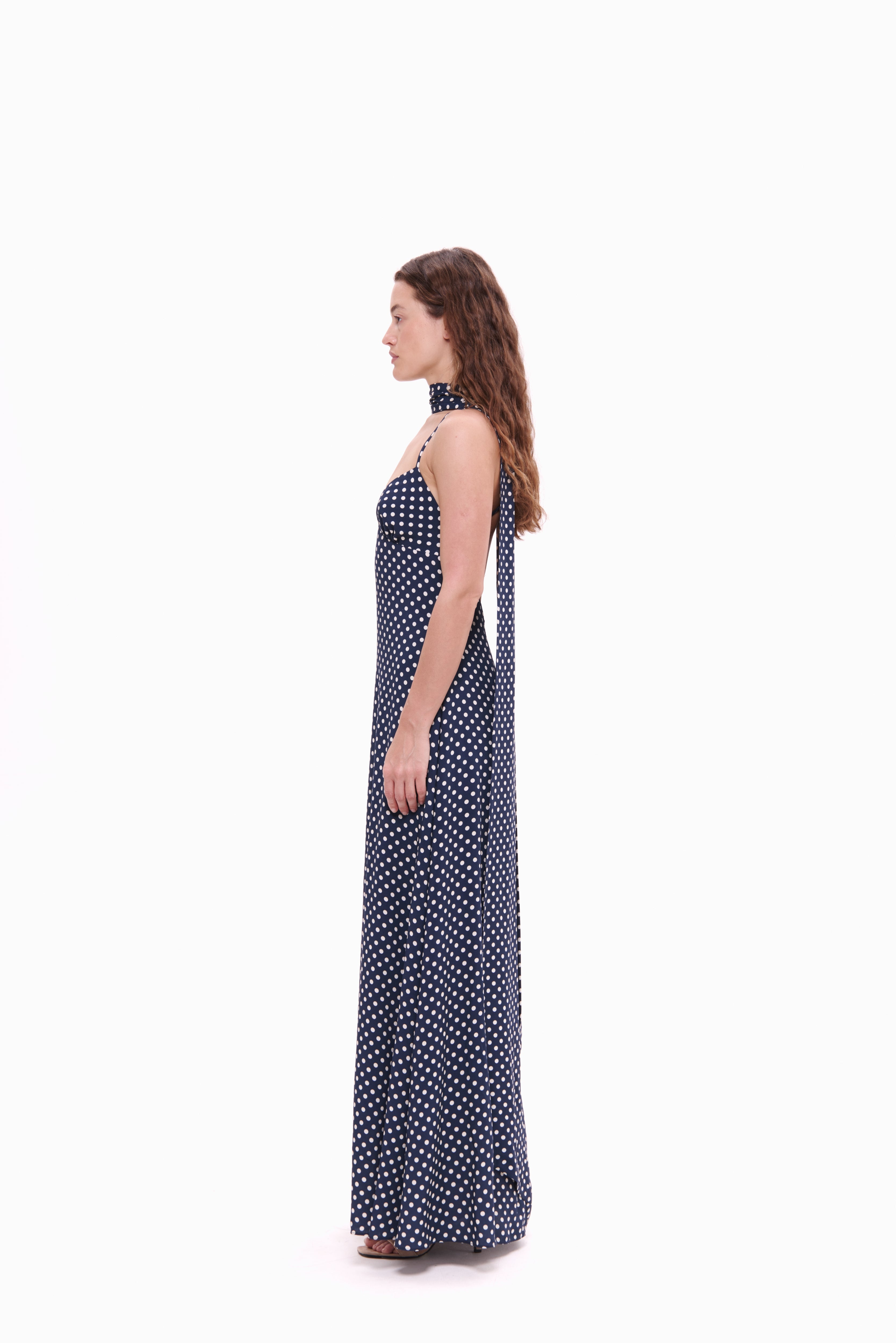 Woman wearing a navy blue polka dot dress on a white background