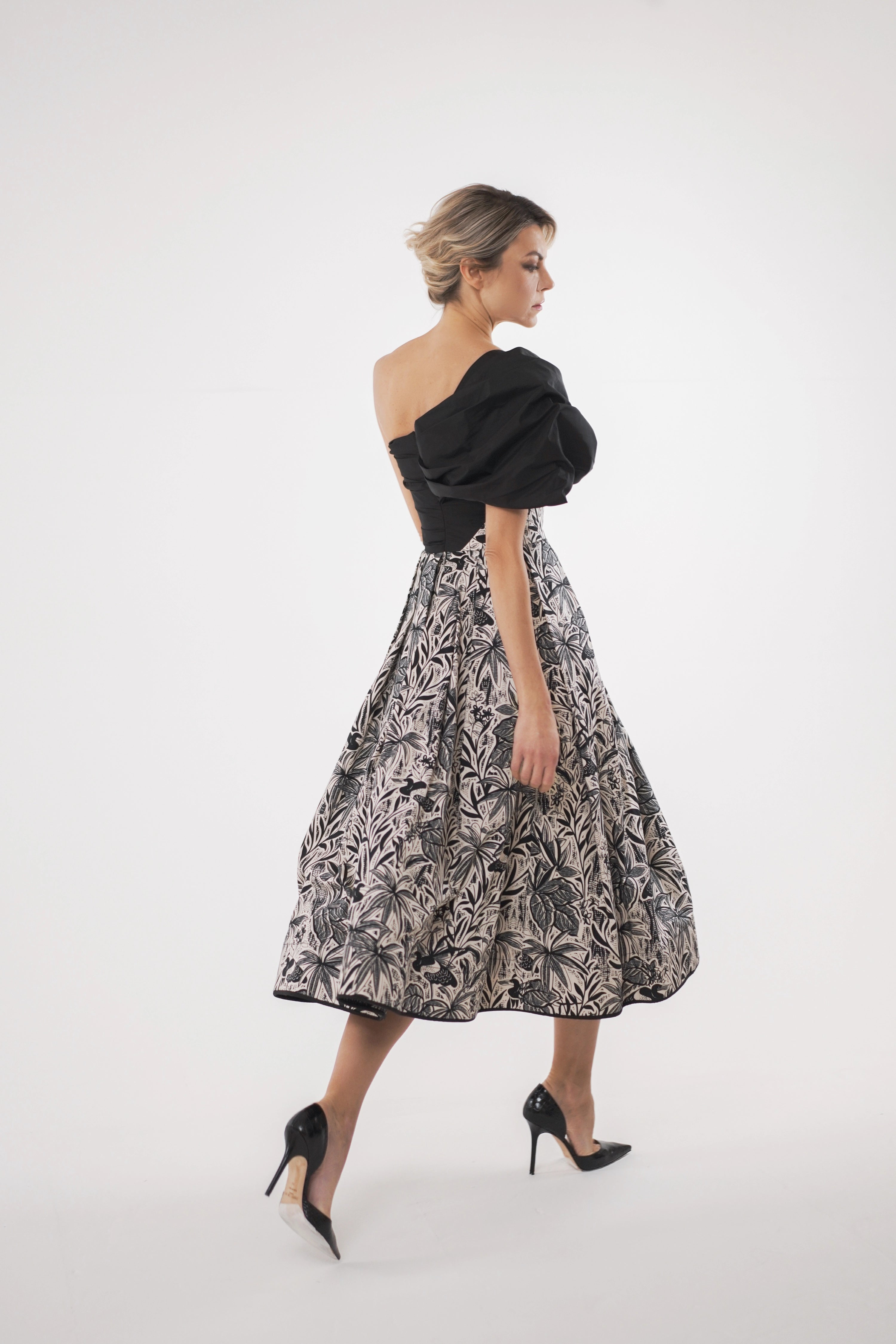 Woman wearing La Muse Nocturne Dress from Mimaussy Paris, side view while walking in studio setting against a plain white background