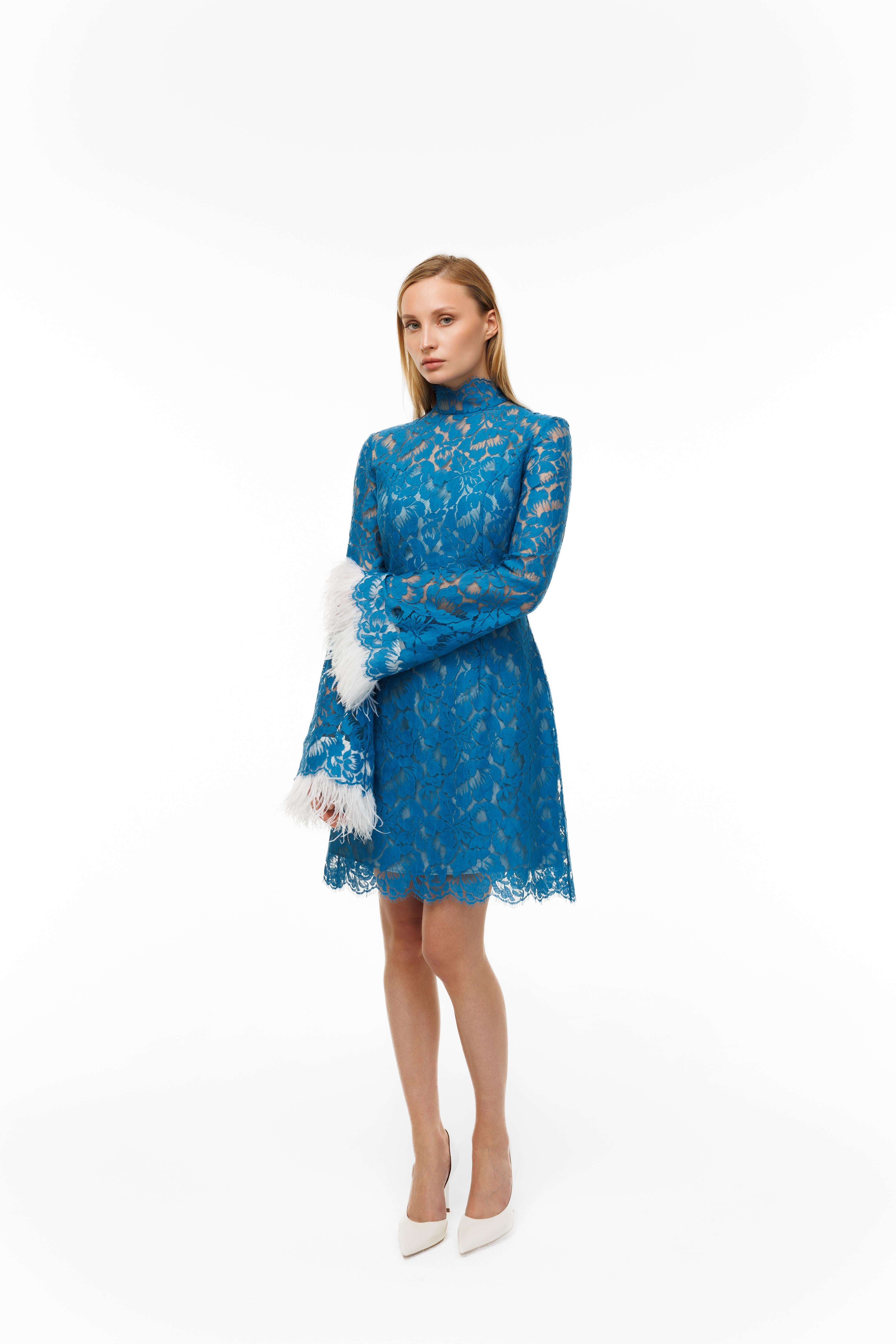 Woman wearing a blue lace dress with white accents on a white background