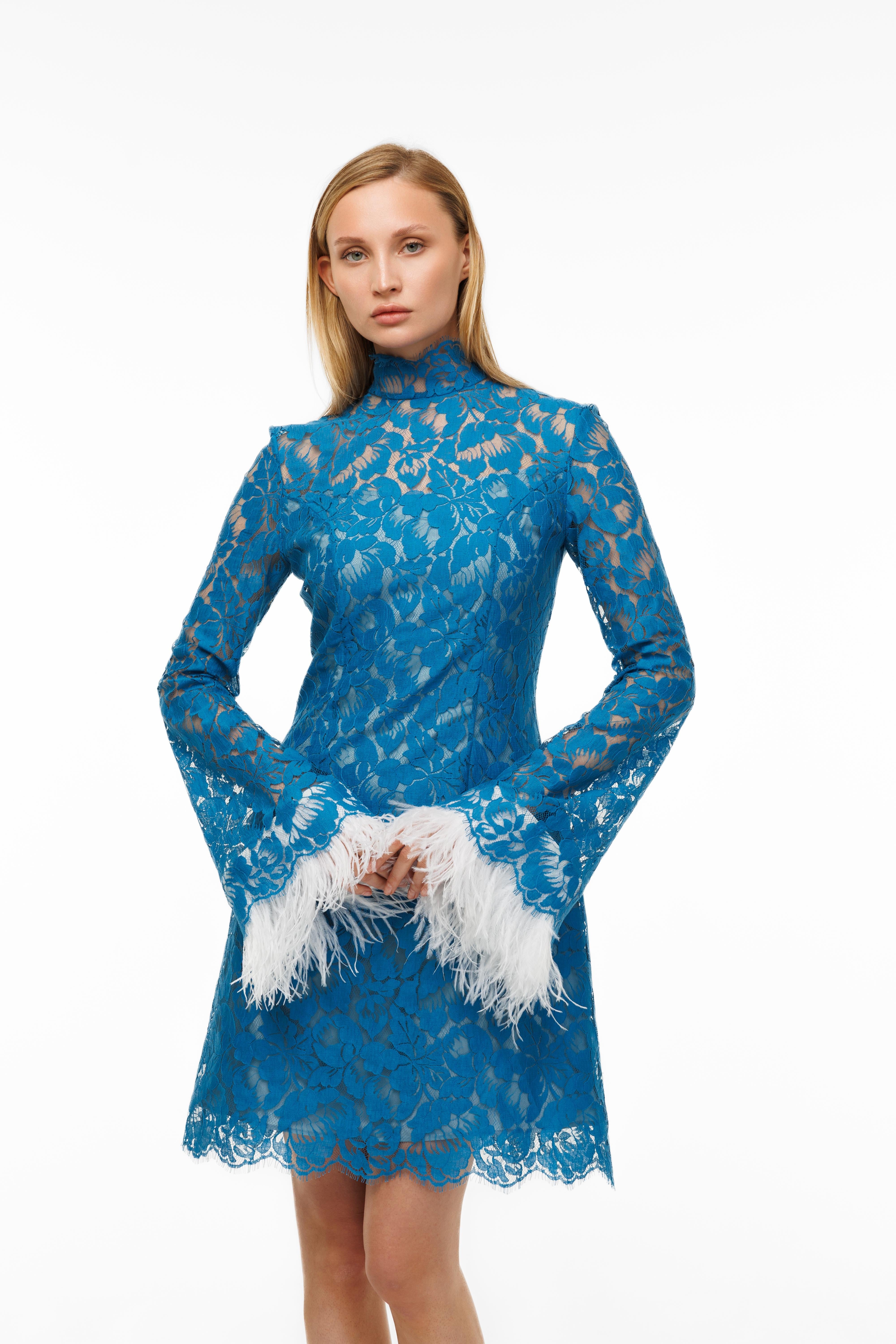 Woman wearing a blue lace dress holding white feathers on a white background