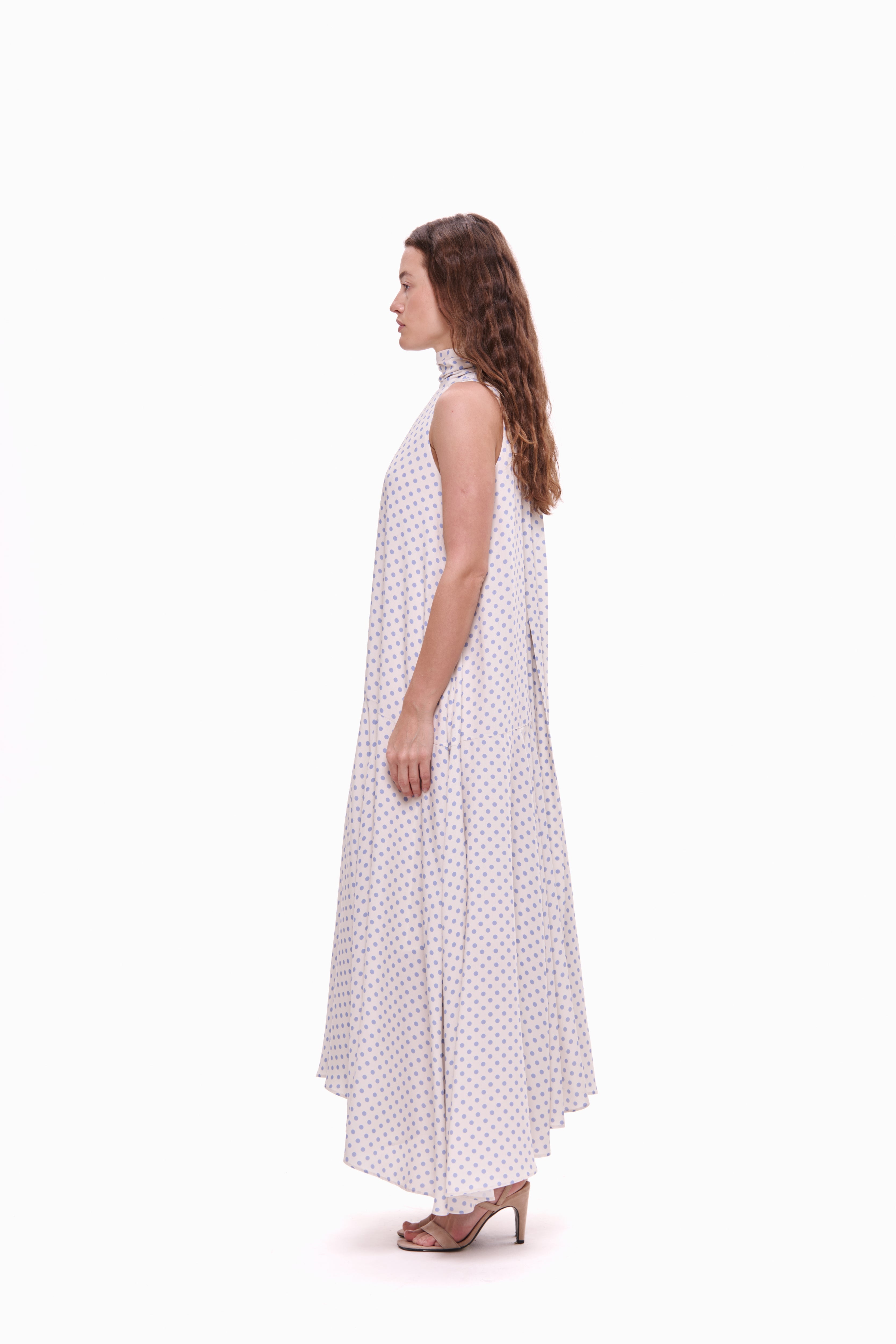 Woman wearing a white dress with lavender polka dots on a white background