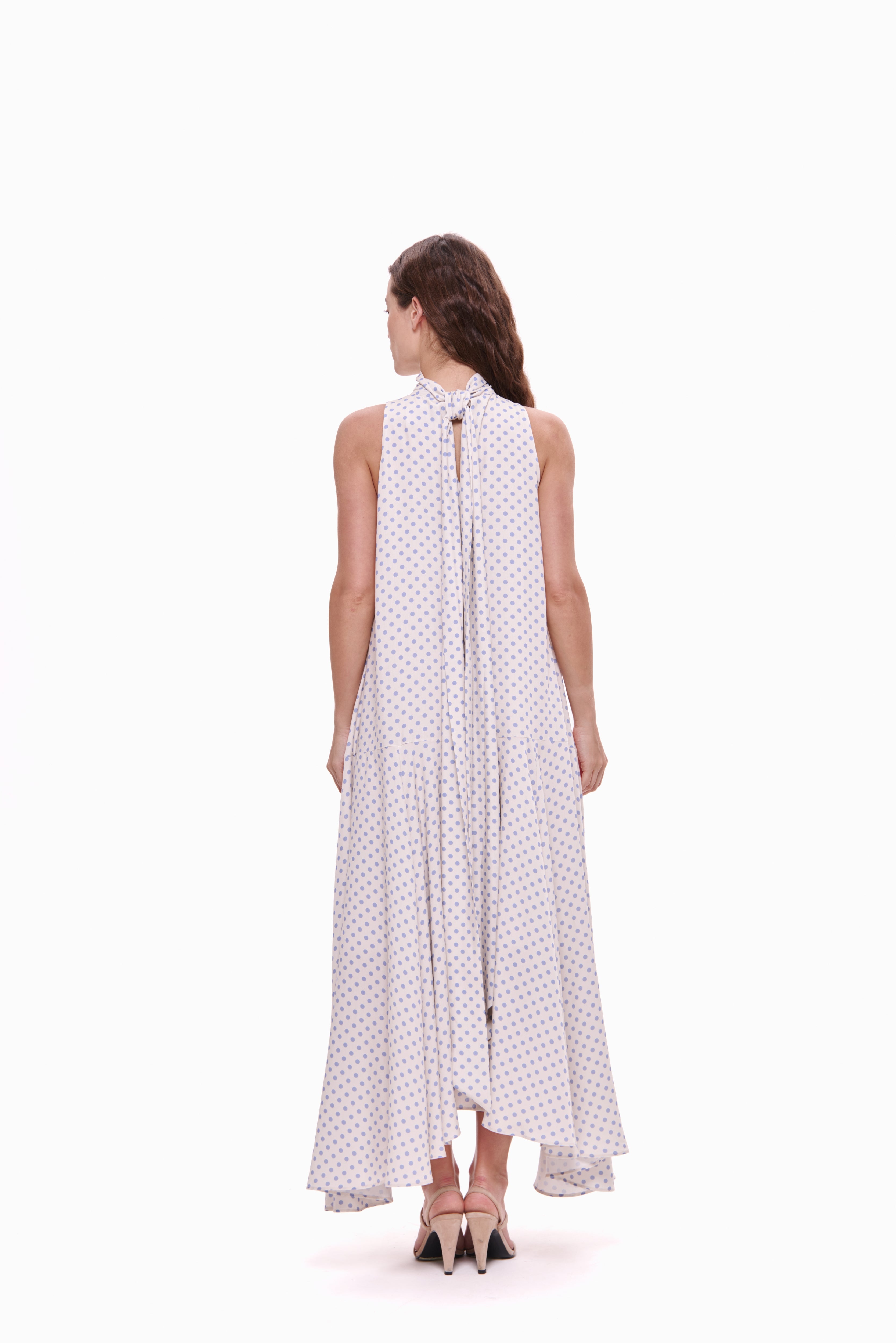 Woman wearing a white dress with black polka dots on a white background