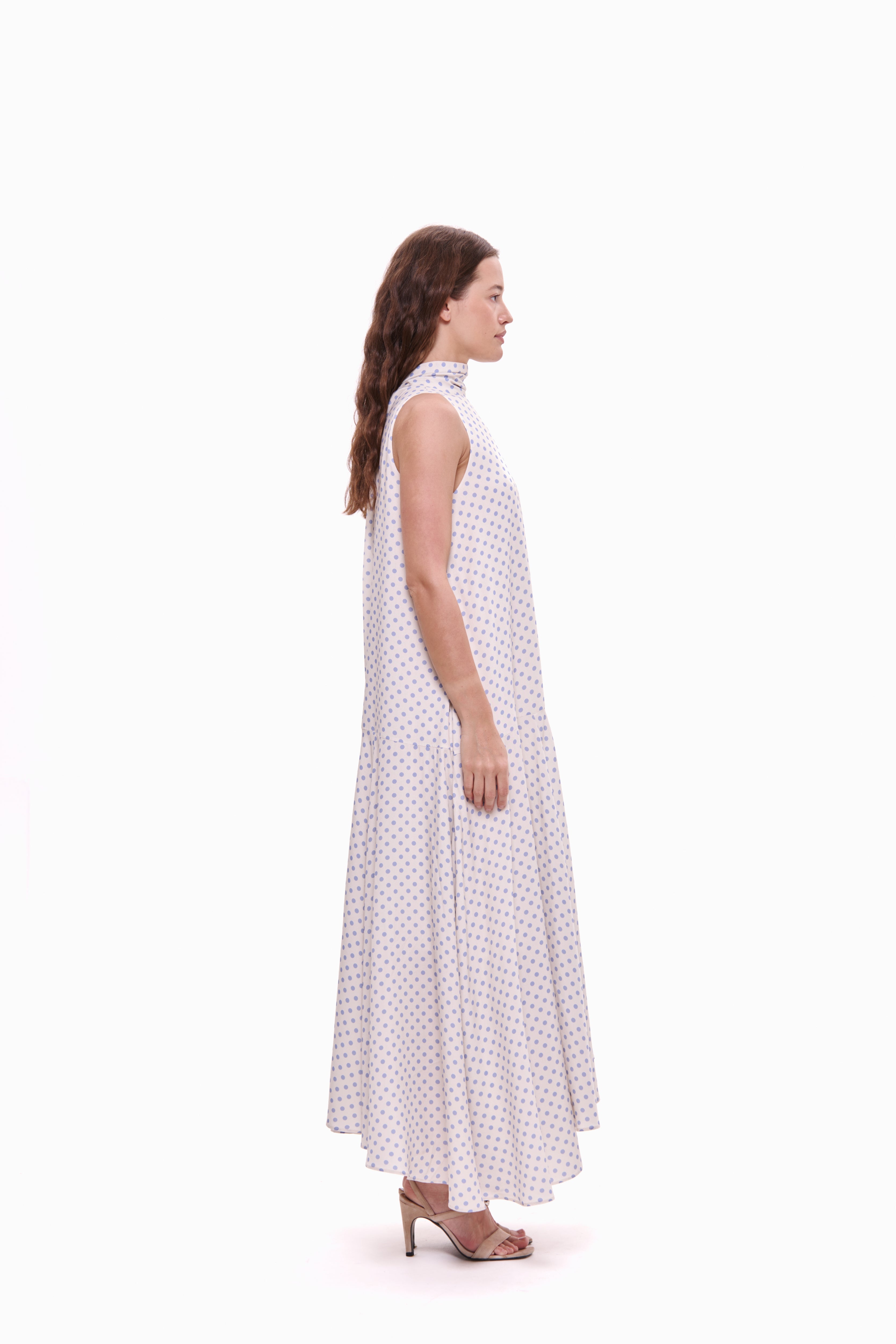 Woman wearing a white dress with lavender polka dots on a white background