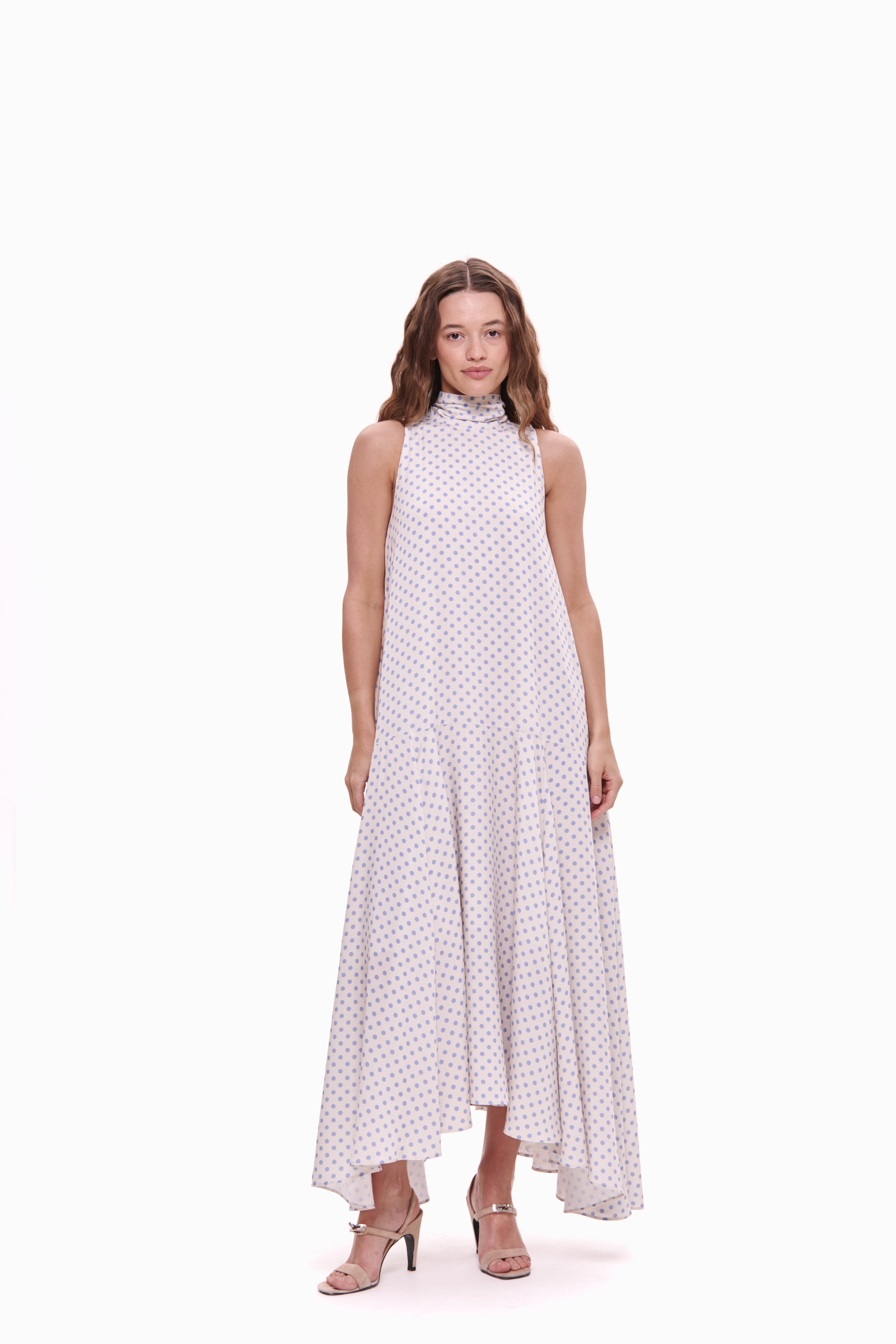 Woman wearing a white dress with lavender polka dots on a white background