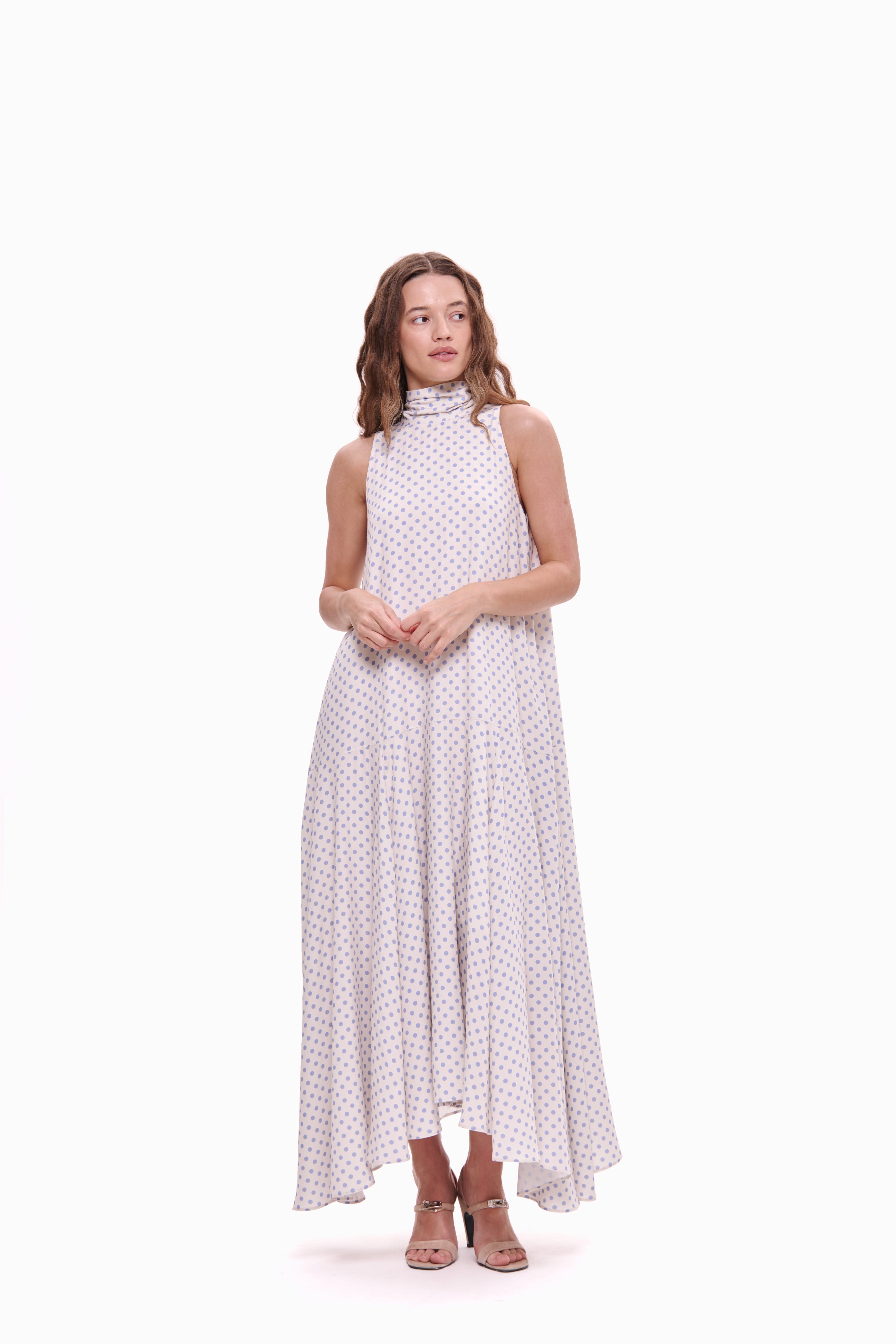 Woman wearing a sleeveless polka dot dress on a white background