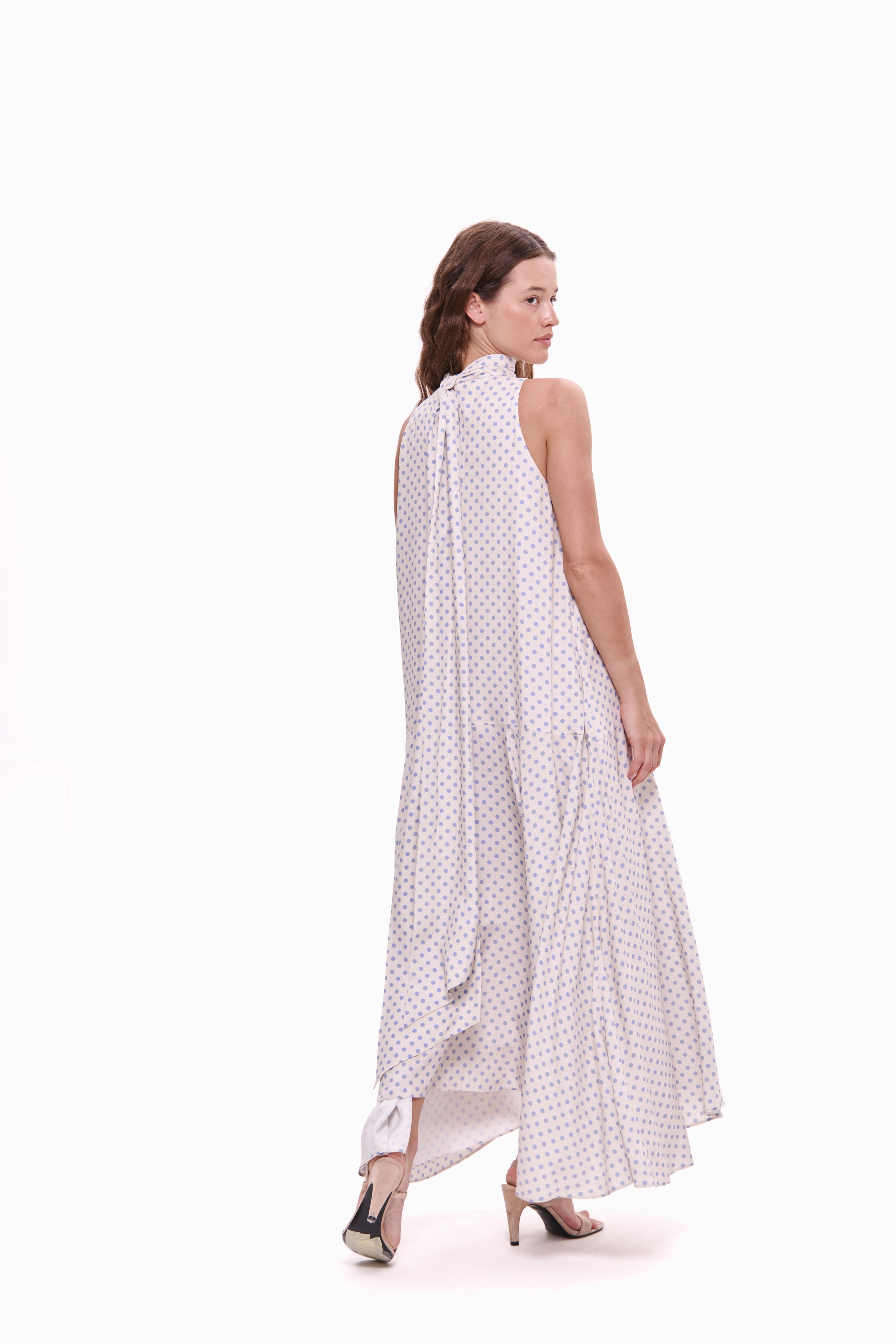 Woman wearing a white dress with black polka dots on a white background