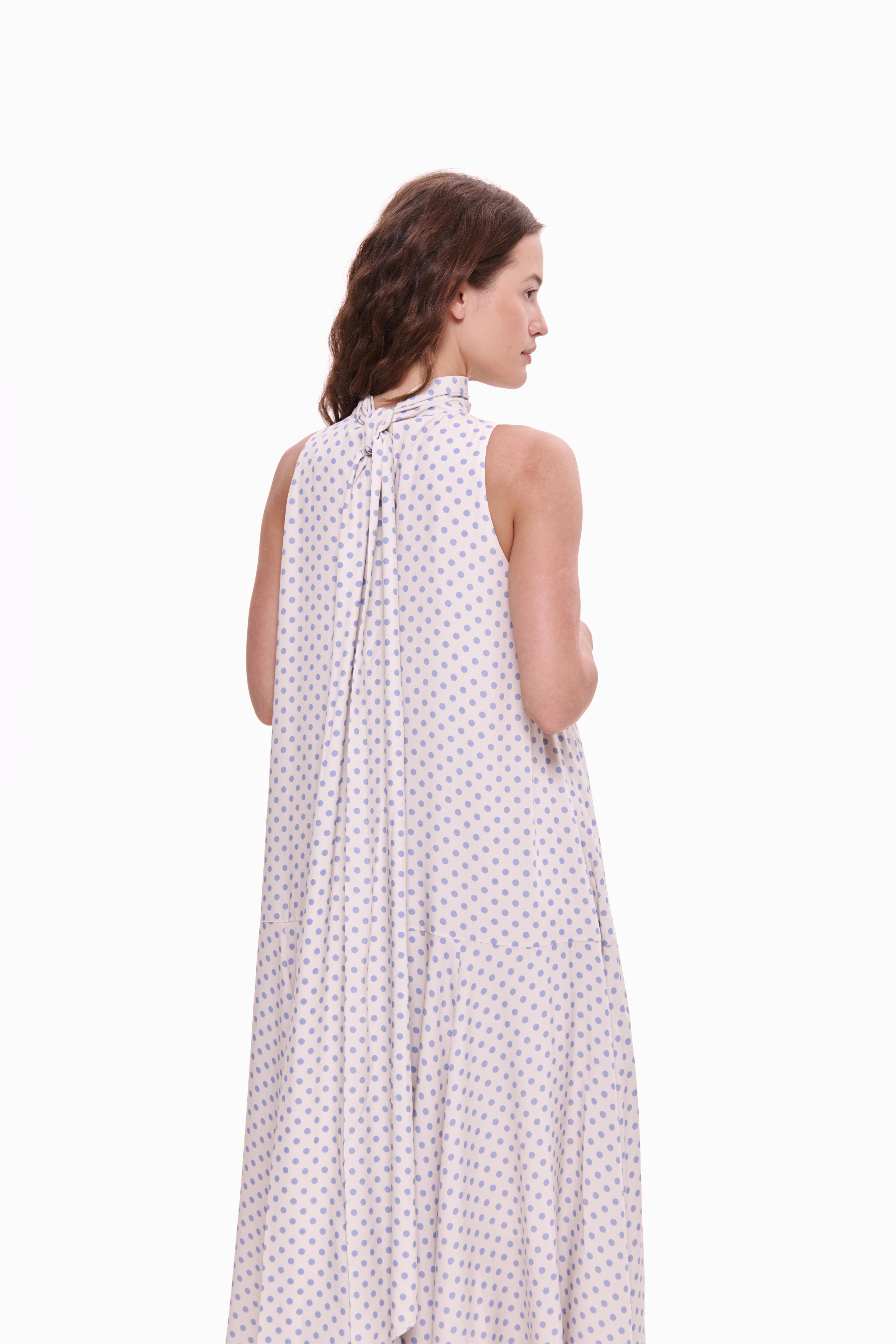Woman wearing a white polka dot dress on a white background