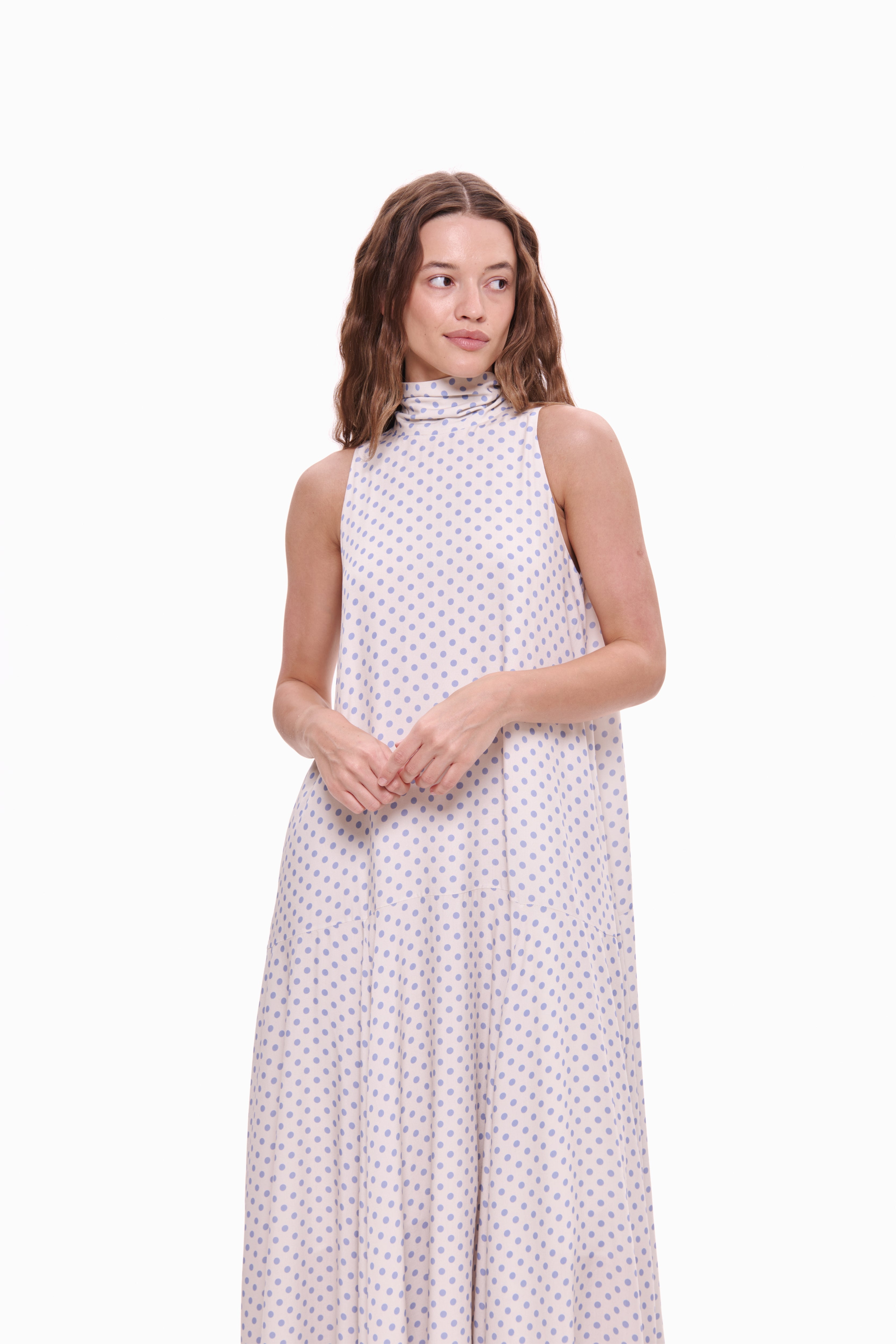 Woman wearing a white dress with pink polka dots on a white background
